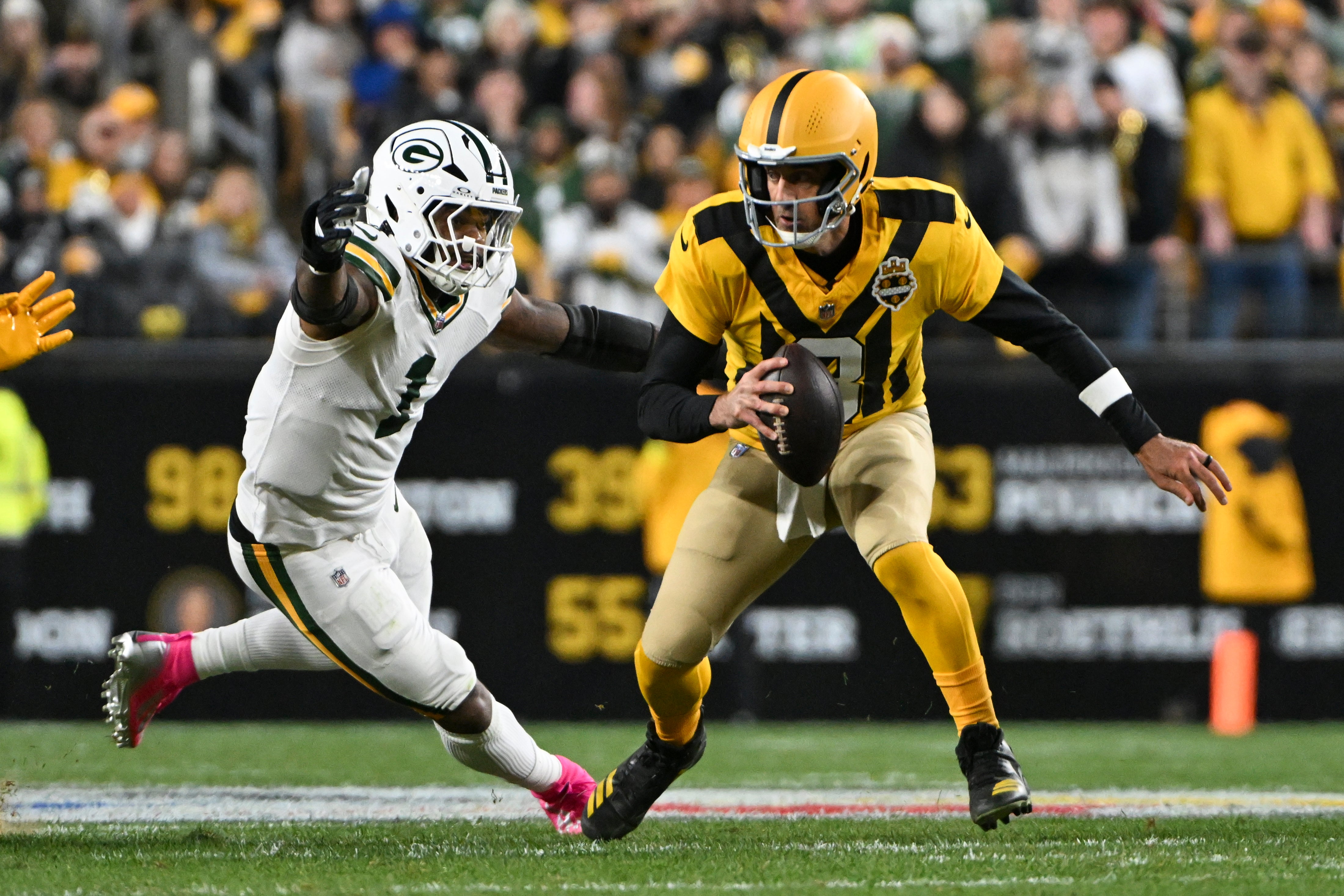 Oct 26, 2025; Pittsburgh, Pennsylvania, USA; Pittsburgh Steelers quarterback Aaron Rodgers (8) scrambles against Green Bay Packers defensive end Micah Parsons (1) during the first quarter at Acrisure Stadium.