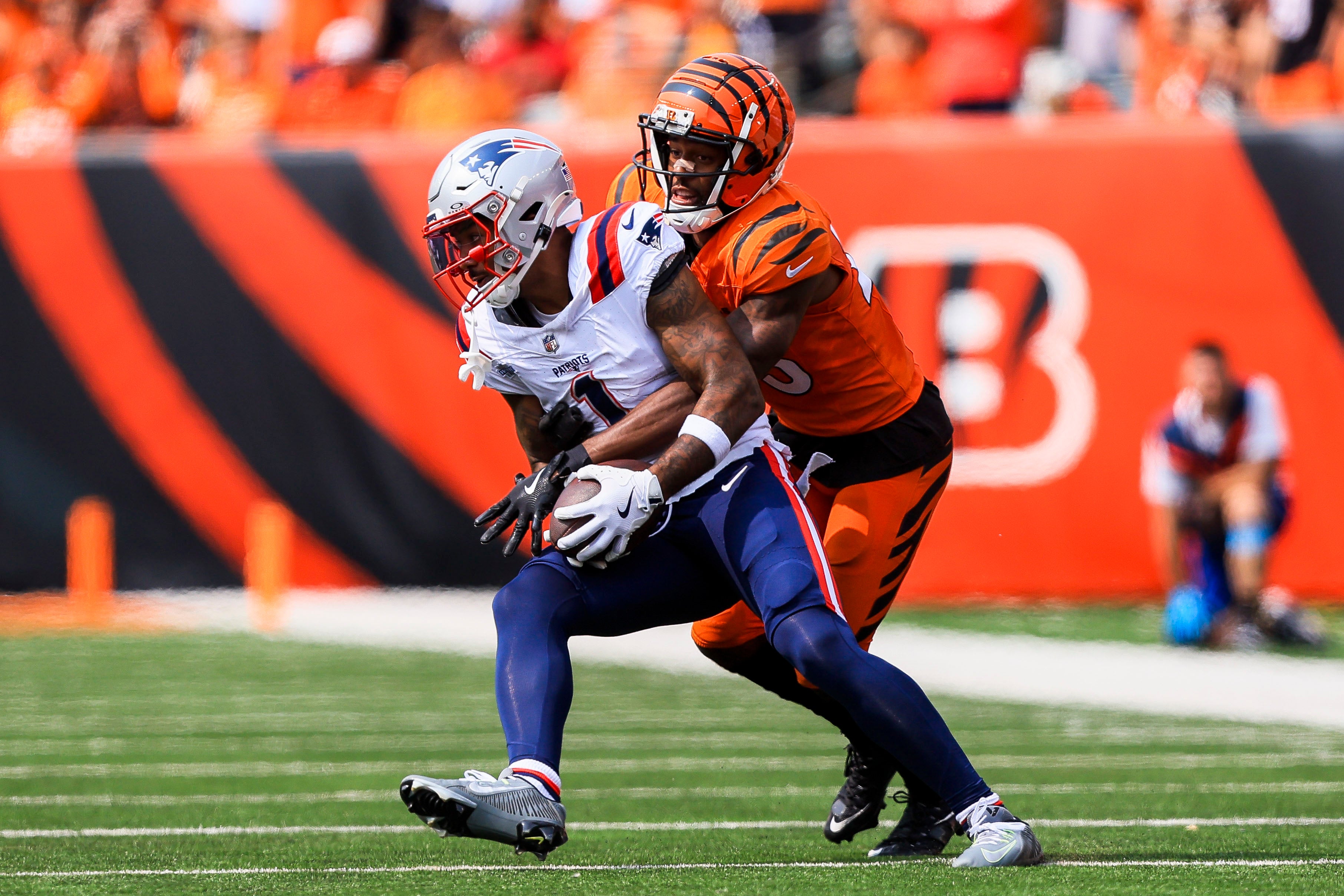 Sep 8, 2024; Cincinnati, Ohio, USA; Cincinnati Bengals cornerback Dax Hill (23) brings down New England Patriots wide receiver Ja'Lynn Polk (1) in the second half at Paycor Stadium.