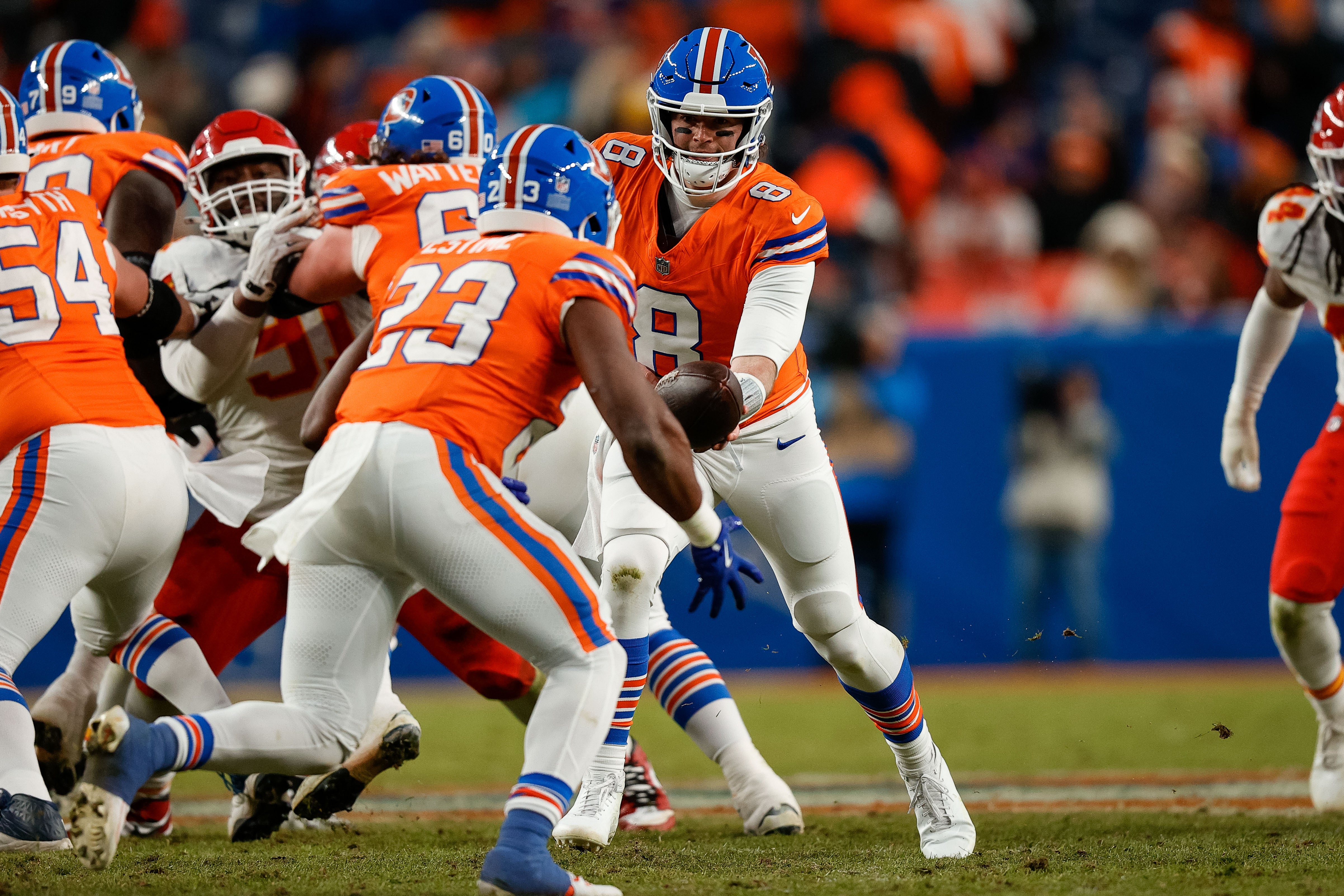 Denver Broncos quarterback Jarrett Stidham (8) hands the ball off to running back Audric Estime (23) in the fourth quarter against the Kansas City Chiefs