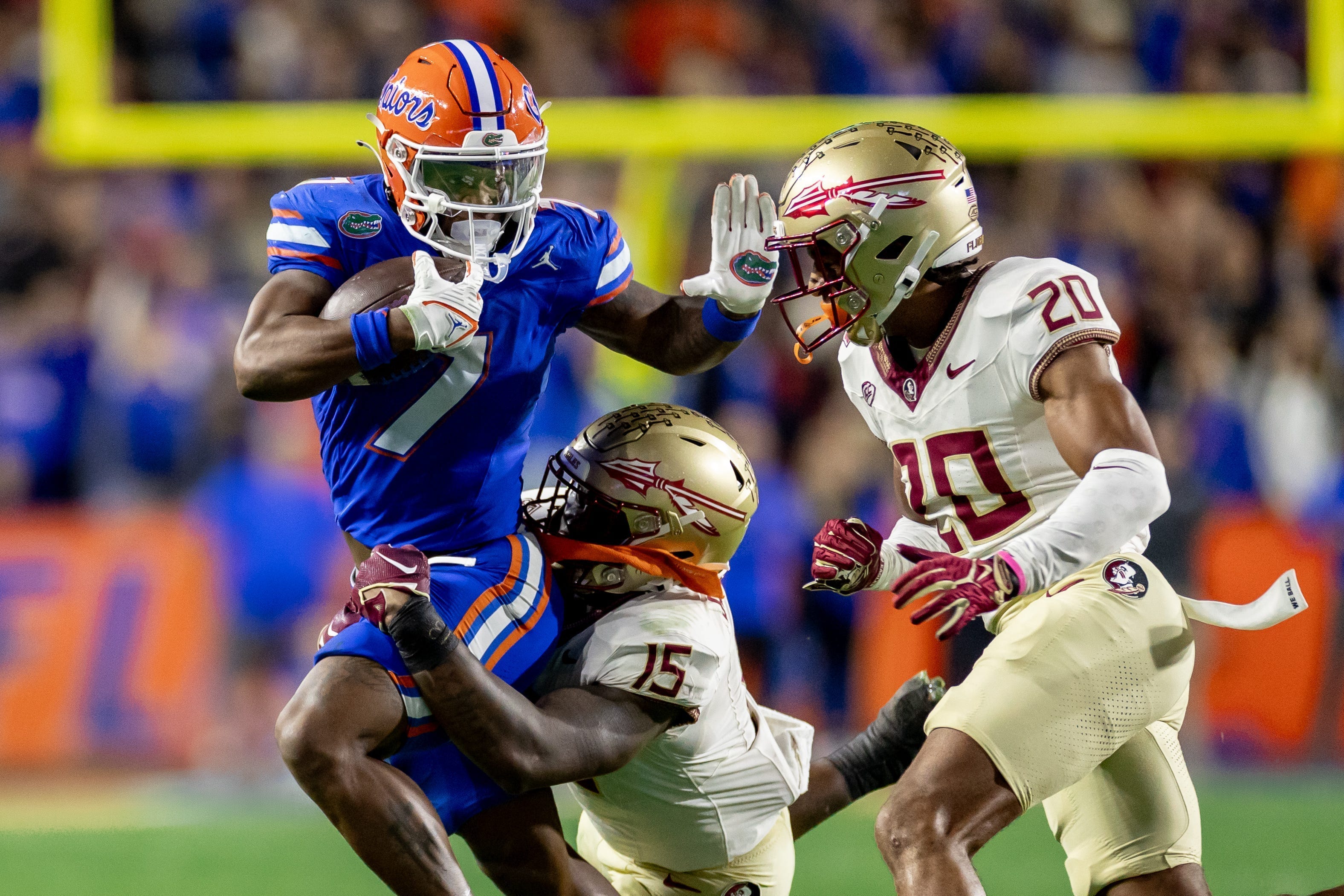Florida Gators running back Trevor Etienne (7) rushes with the ball while Florida State Seminoles linebacker Tatum Bethune (15) and Florida State Seminoles defensive back Azareye'h Thomas (20) attempt to tackle during the first half at Steve Spurrier Field at Ben Hill Griffin Stadium in Gainesville, FL on Saturday, November 25, 2023.