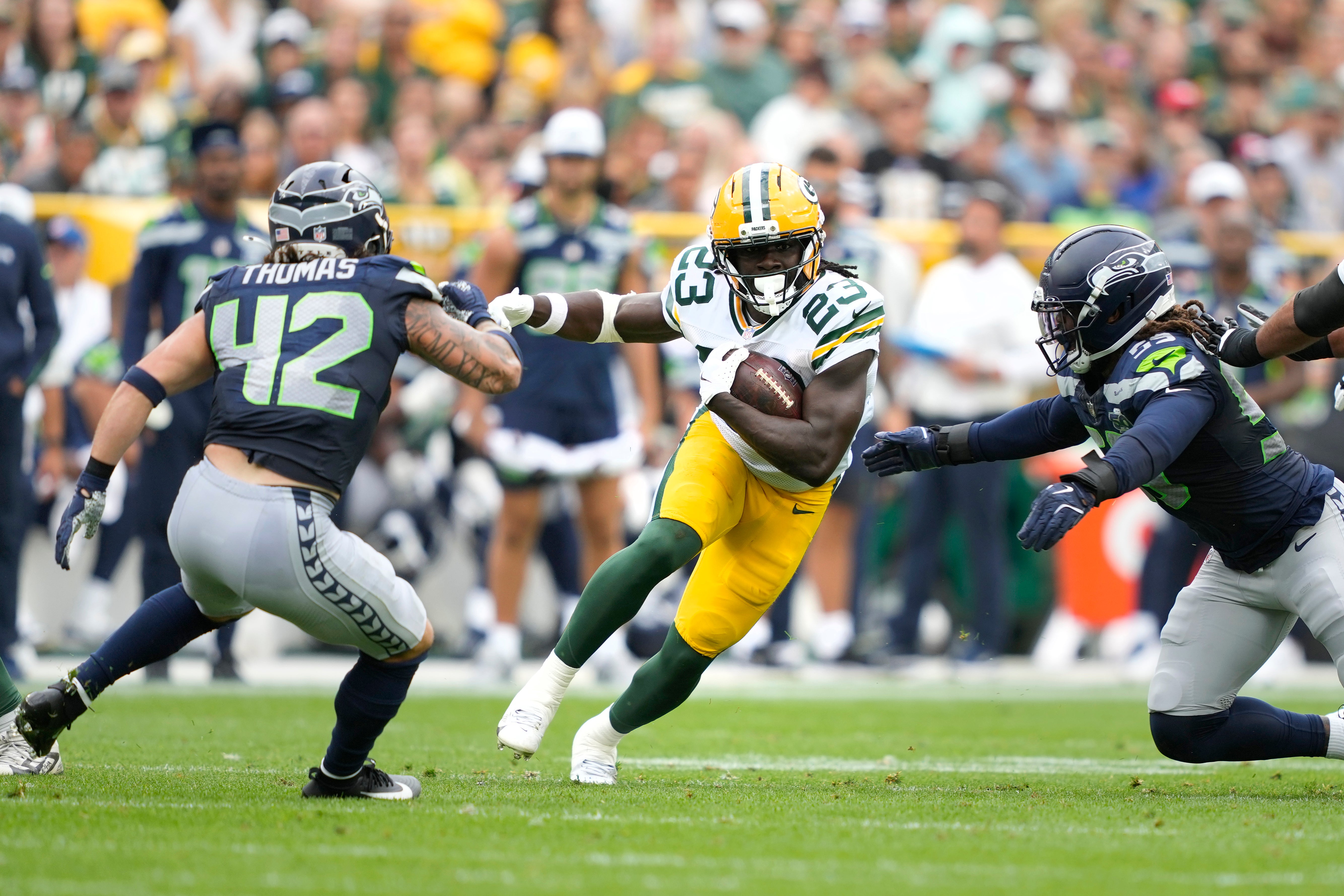 Aug 23, 2025; Green Bay, Wisconsin, USA; Green Bay Packers running back Israel Abanikanda (23) runs the ball against Seattle Seahawks linebacker Drake Thomas (42) and Seattle Seahawks linebacker Tyreke Smith (59) during the first half at Lambeau Field.