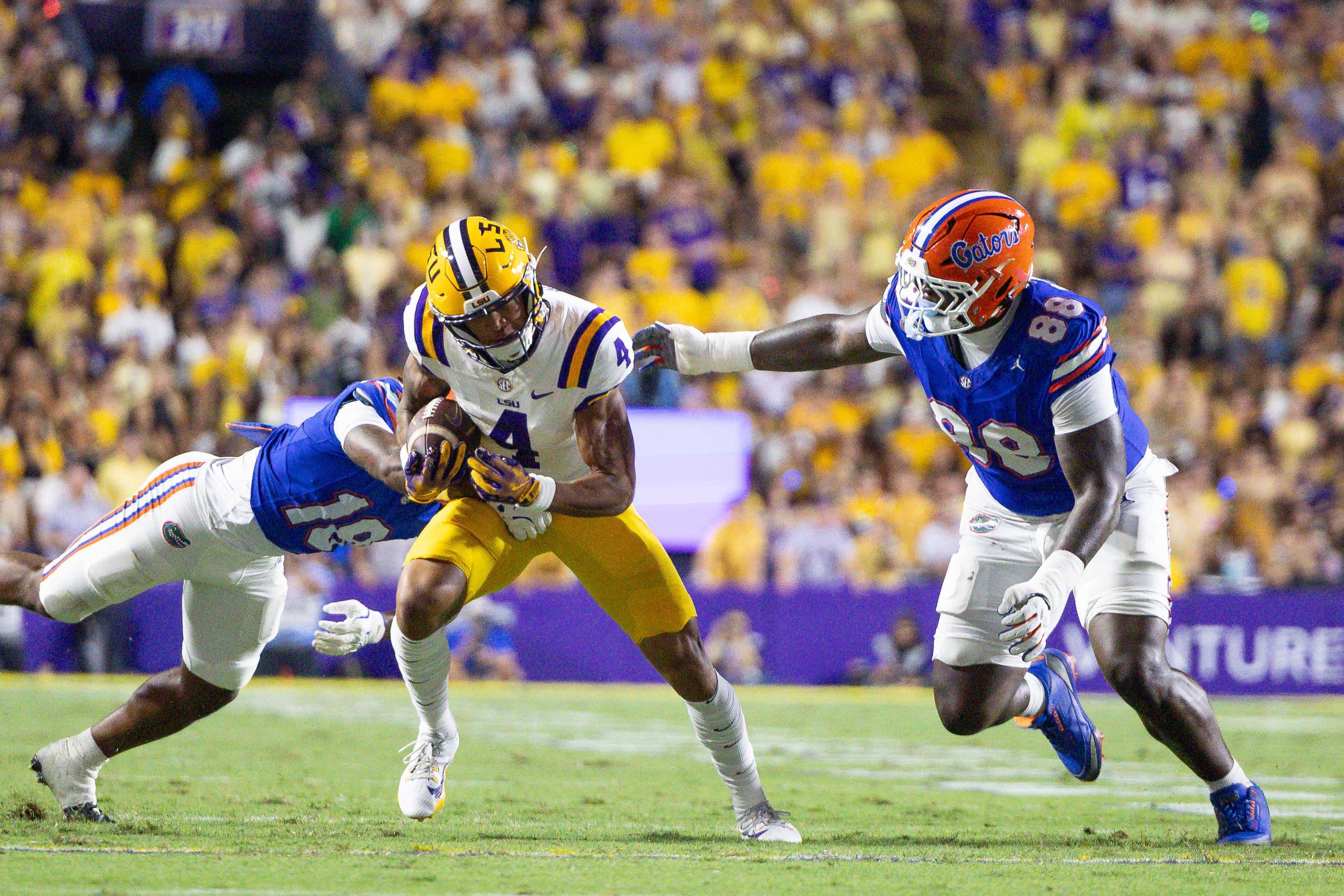 Sep 13, 2025; Baton Rouge, Louisiana, USA; LSU Tigers wide receiver Nic Anderson (4) runs against Florida Gators defensive lineman Caleb Banks (88) and defensive back Bryce Thornton (18) during the first half at Tiger Stadium.