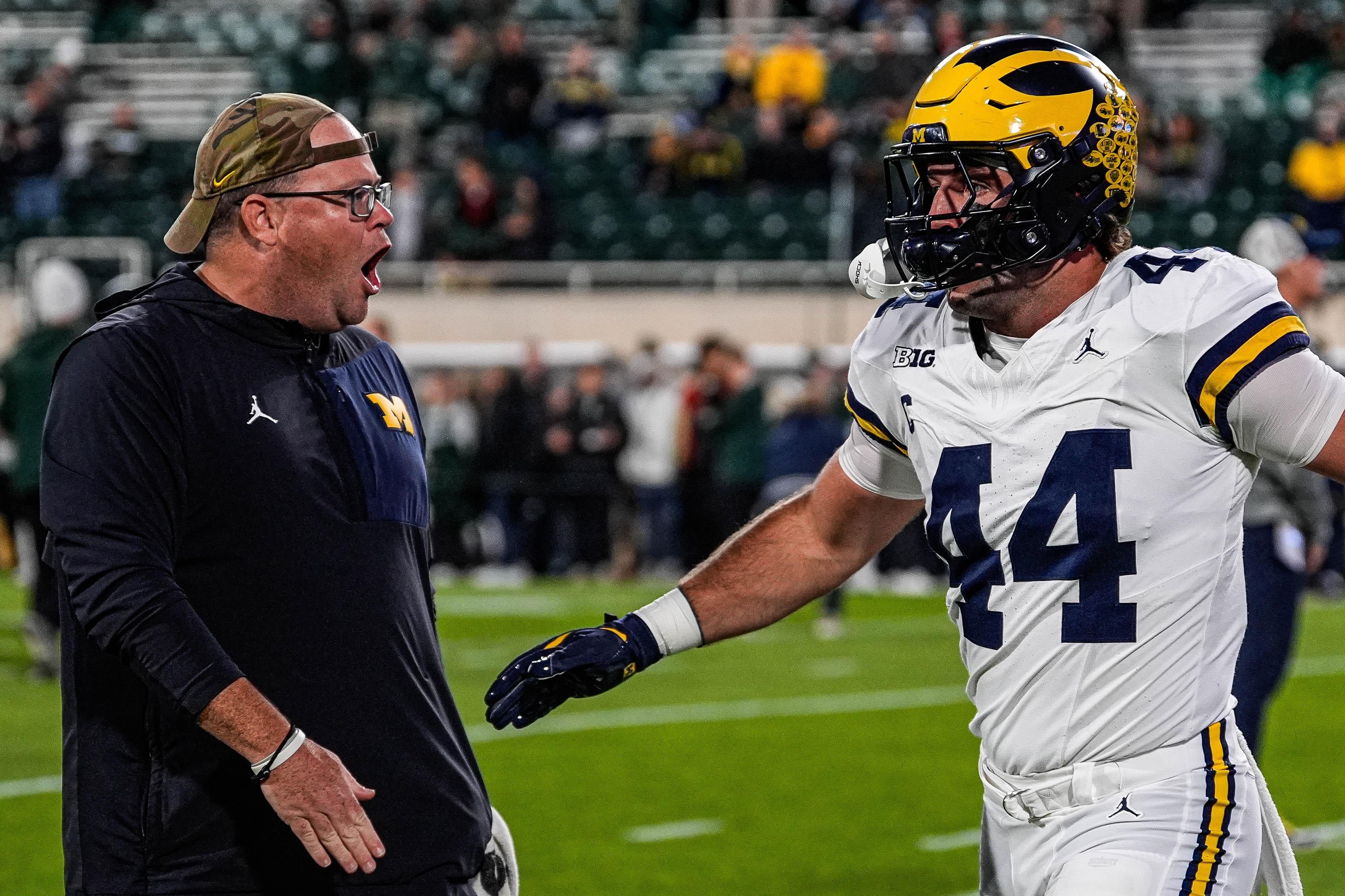 Michigan tight end Max Bredeson shakes hands with tight ends coach Steve Casula during warmups at Spartan Stadium in East Lansing on Saturday, October 25, 2025.