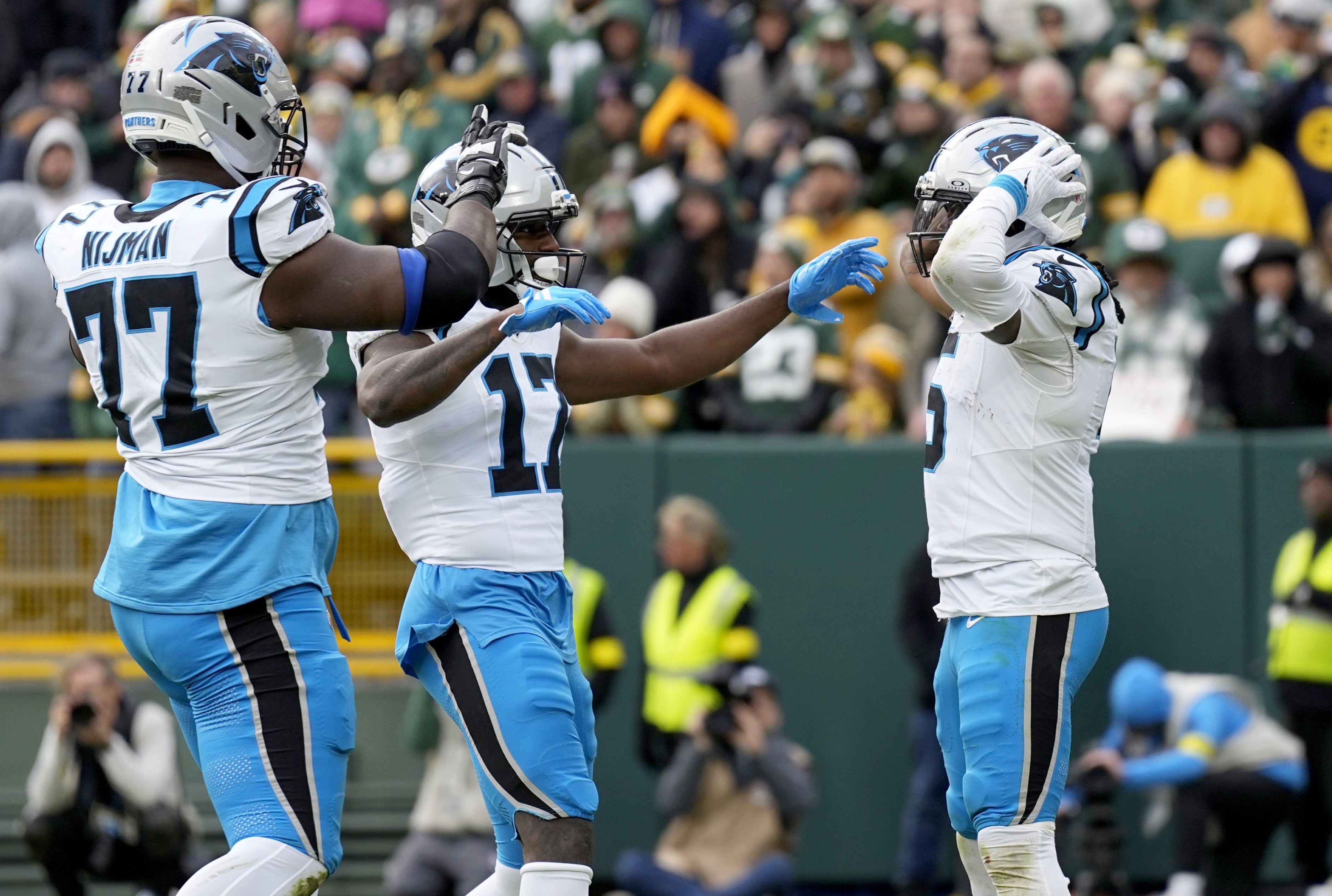 Nov 2, 2025; Green Bay, Wisconsin, USA; Carolina Panthers running back Rico Dowdle (5) celebrates with offensive tackle Yosh Nijman (77) and wide receiver Xavier Legette (17) after a touchdown during the second half against the Green Bay Packers at Lambeau Field.