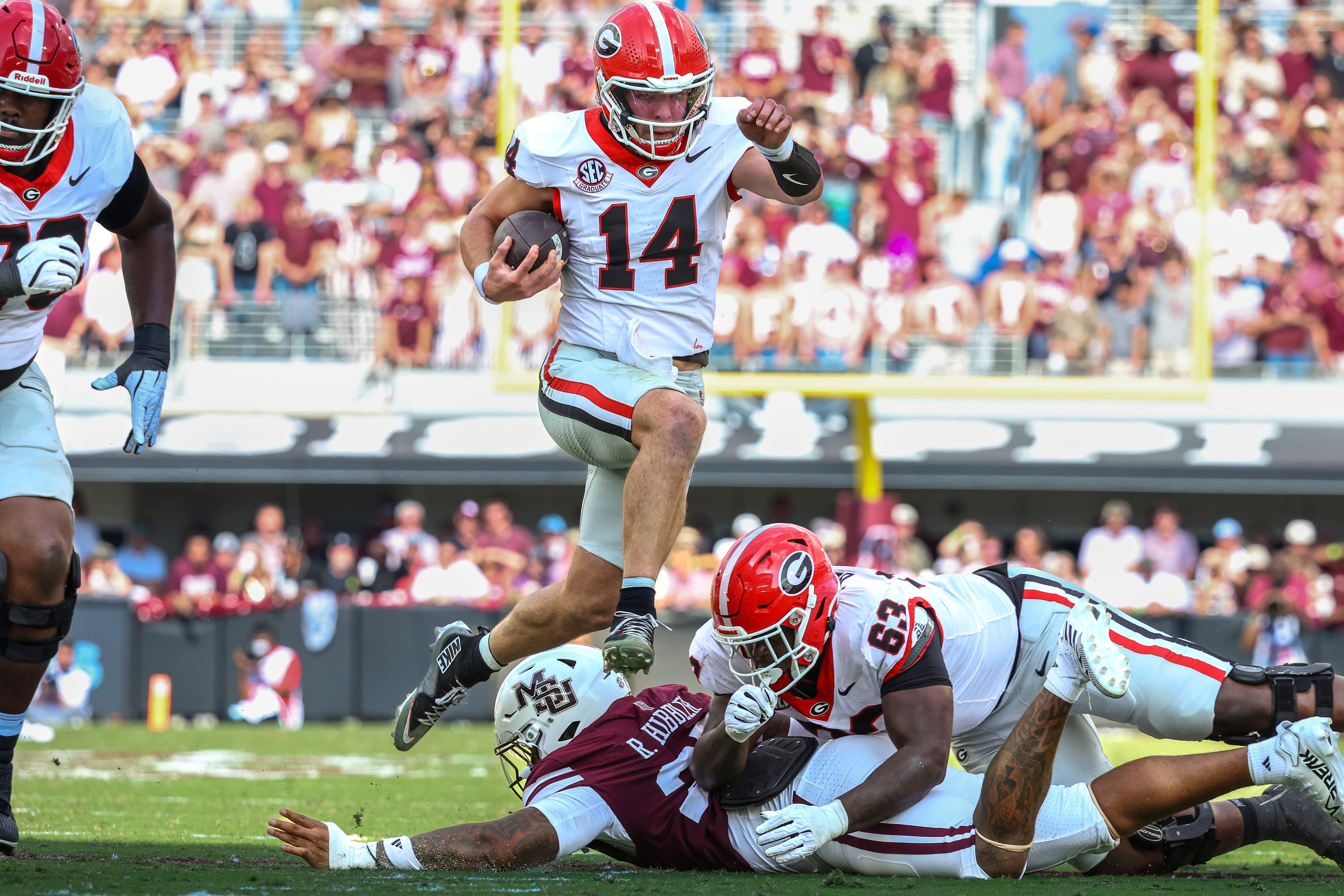Georgia Bulldogs quarterback Gunner Stockton (14) runs with the ball against the Mississippi State Bulldogs during the first half at Davis Wade Stadium at Scott Field.