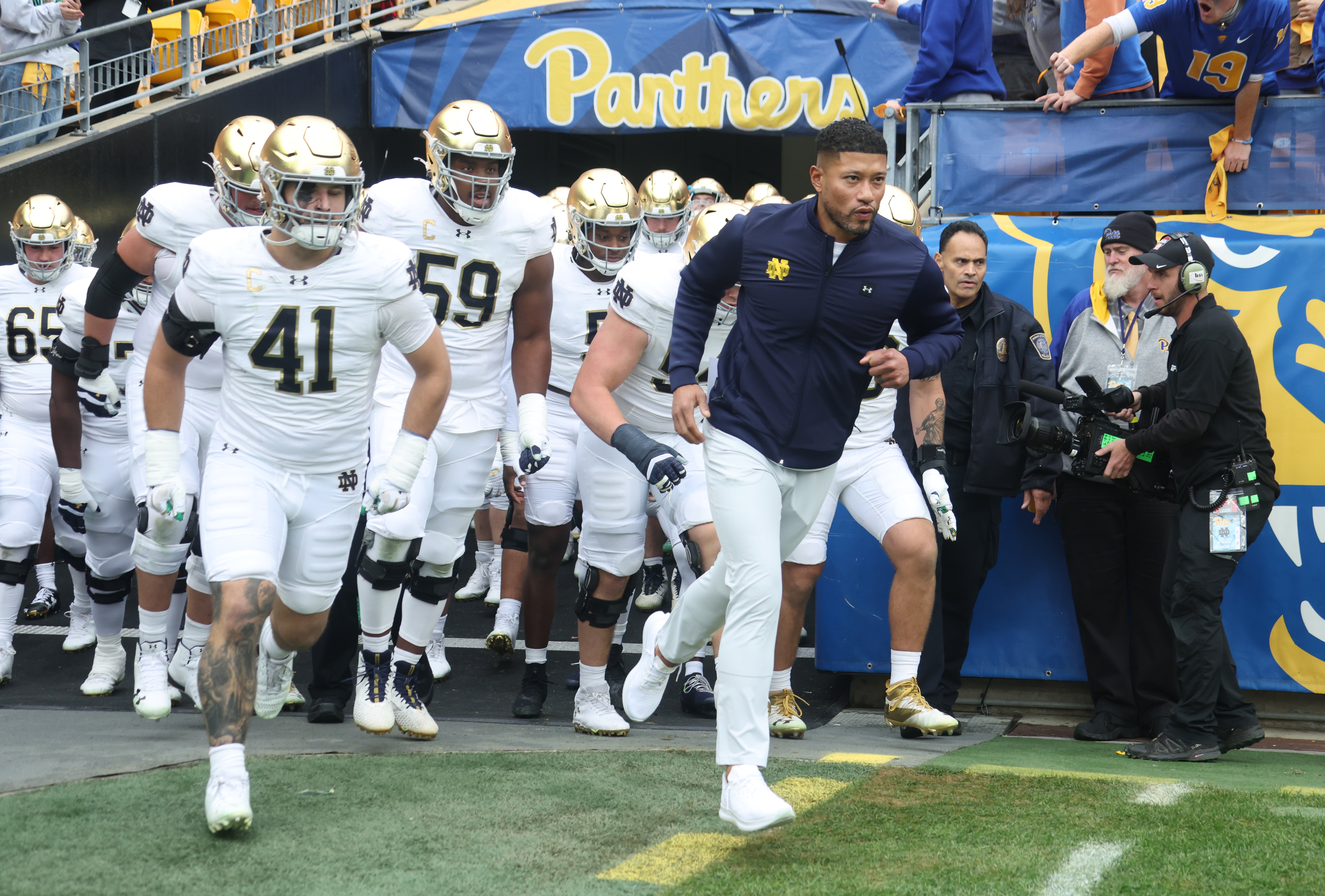 Nov 15, 2025; Pittsburgh, Pennsylvania, USA; Notre Dame Fighting Irish head coach Marcus Freeman (right) leads the team onto the field to play the Pittsburgh Panthers at Acrisure Stadium. Mandatory Credit: Charles LeClaire-Imagn Images