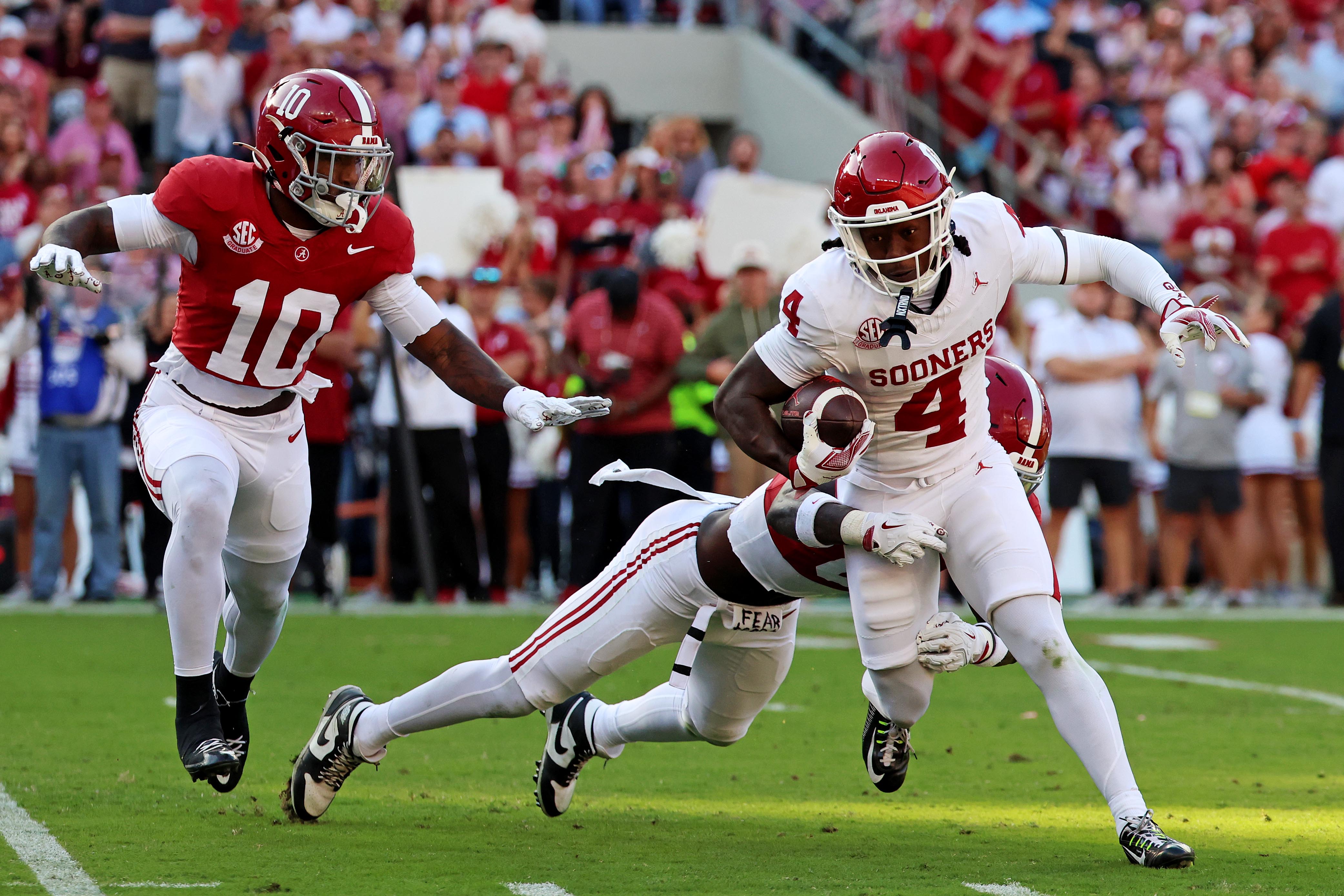 Nov 15, 2025; Tuscaloosa, Alabama, USA; Oklahoma Sooners wide receiver Deion Burks (4) runs the ball against Alabama Crimson Tide linebacker Deontae Lawson (0) during the first half at Saban Field at Bryant-Denny Stadium.