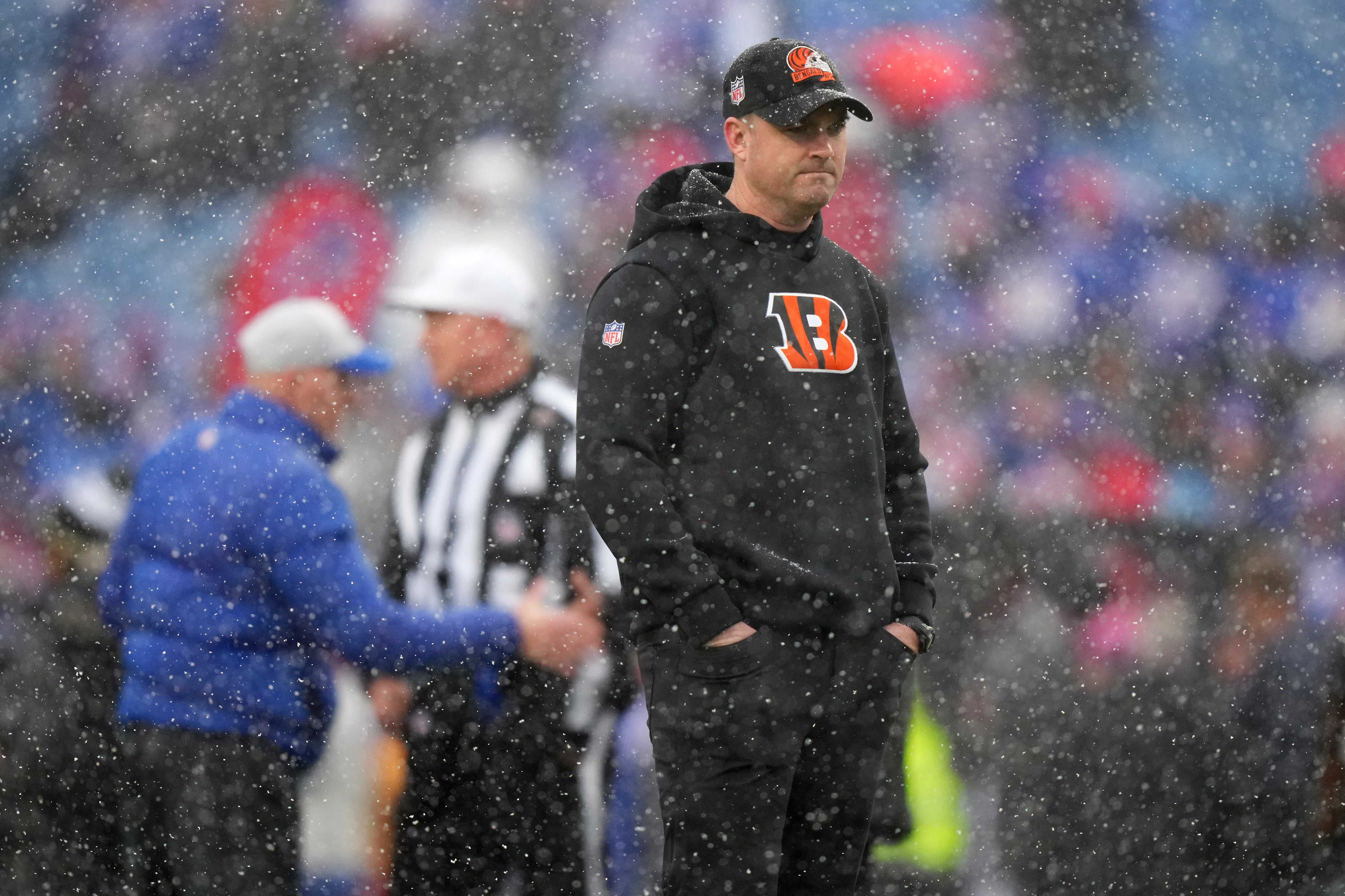 Jan 22, 2023; Orchard Park, New York, USA; Cincinnati Bengals head coach Zac Taylor observes the team warming up as Buffalo Bills head coach Sean McDermott, background, shakes hands with game officials before an AFC divisional round game between the Buffalo Bills and the Cincinnati Bengals at Highmark Stadium.