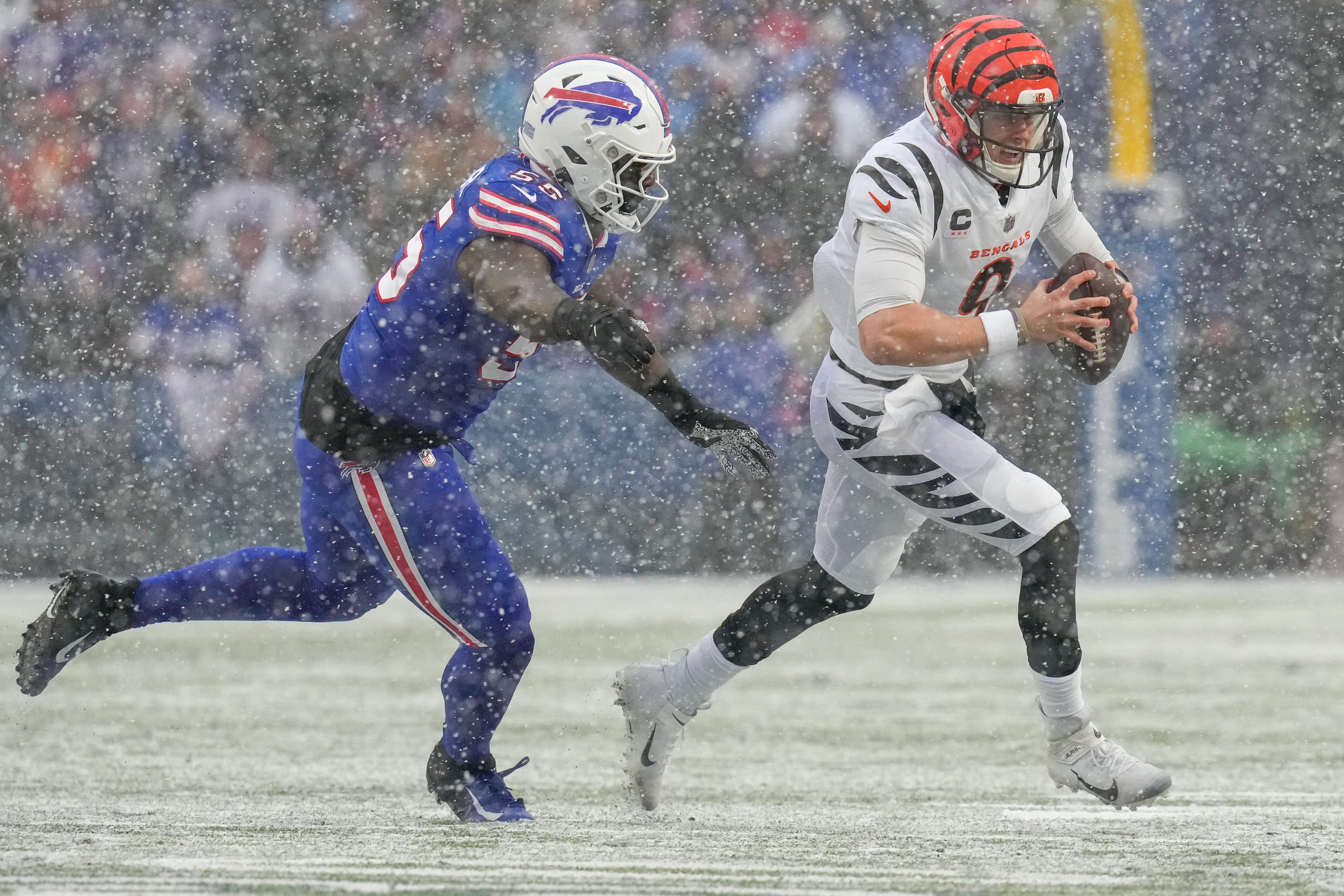 Cincinnati Bengals quarterback Joe Burrow (9) scrambles under pressure from Buffalo Bills defensive end Boogie Basham (55) in the first quarter of the NFL divisional playoff football game between the Cincinnati Bengals and the Buffalo Bills, Sunday, Jan. 22, 2023, at Highmark Stadium in Orchard Park, N.Y.