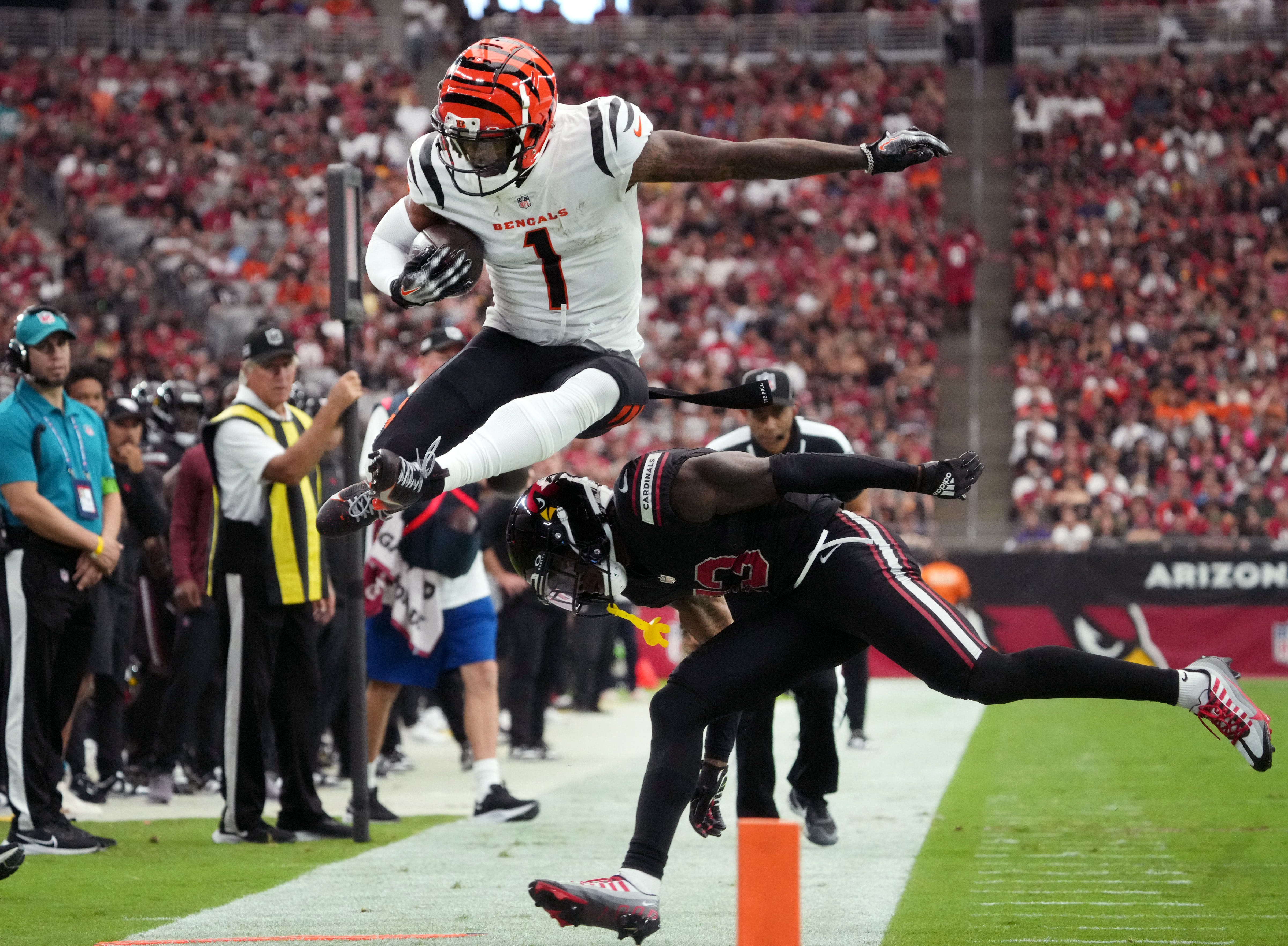 Cincinnati Bengals receiver Ja'Marr Chase (1) leaps over Arizona Cardinals cornerback Kei'Trel Clark (13) at State Farm Stadium in Glendale on Oct. 8, 2023.