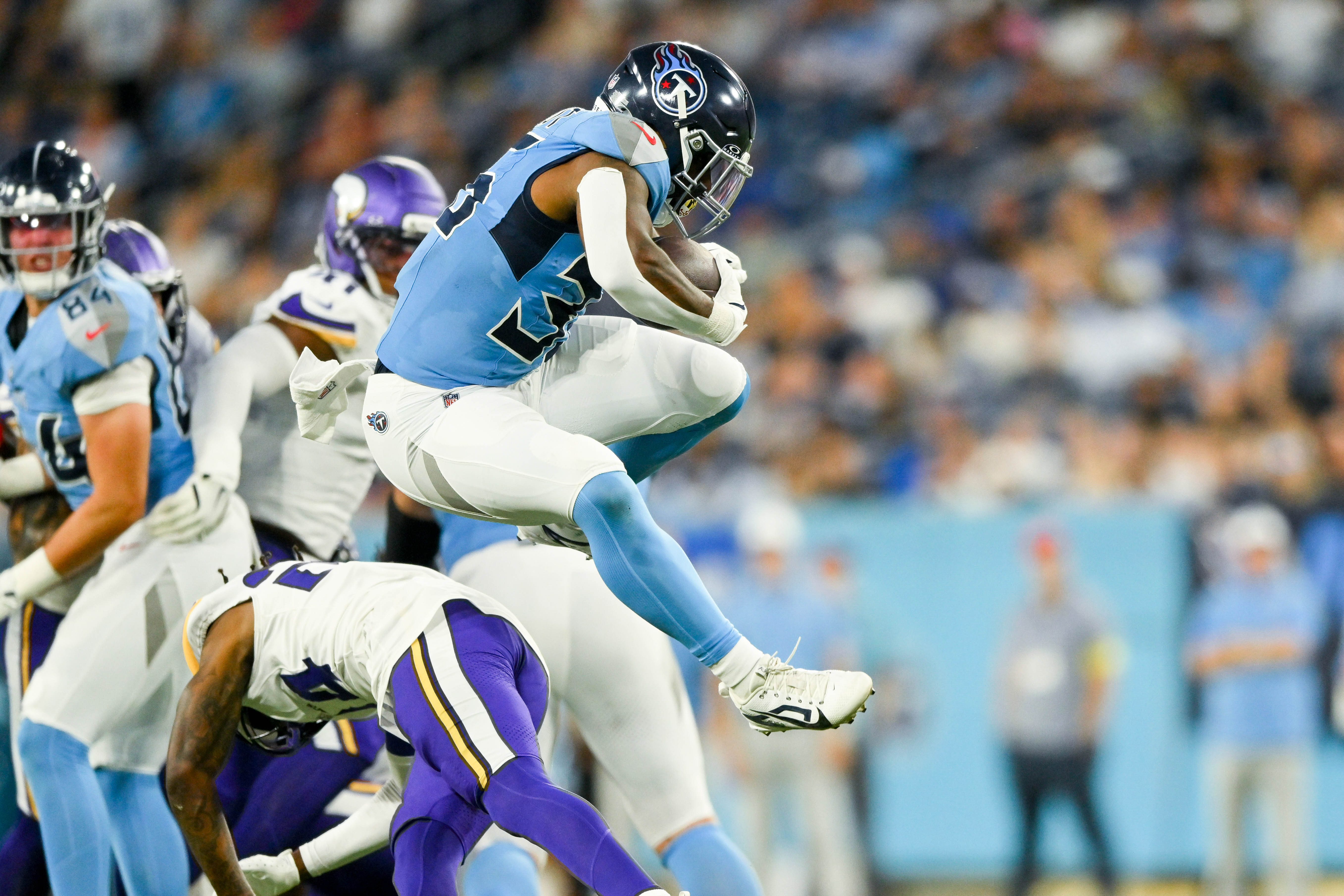 Aug 22, 2025; Nashville, Tennessee, USA; Tennessee Titans cornerback Jalen Kimber (35) hurdles Minnesota Vikings linebacker Cam Gill (28) during the first half at Nissan Stadium.