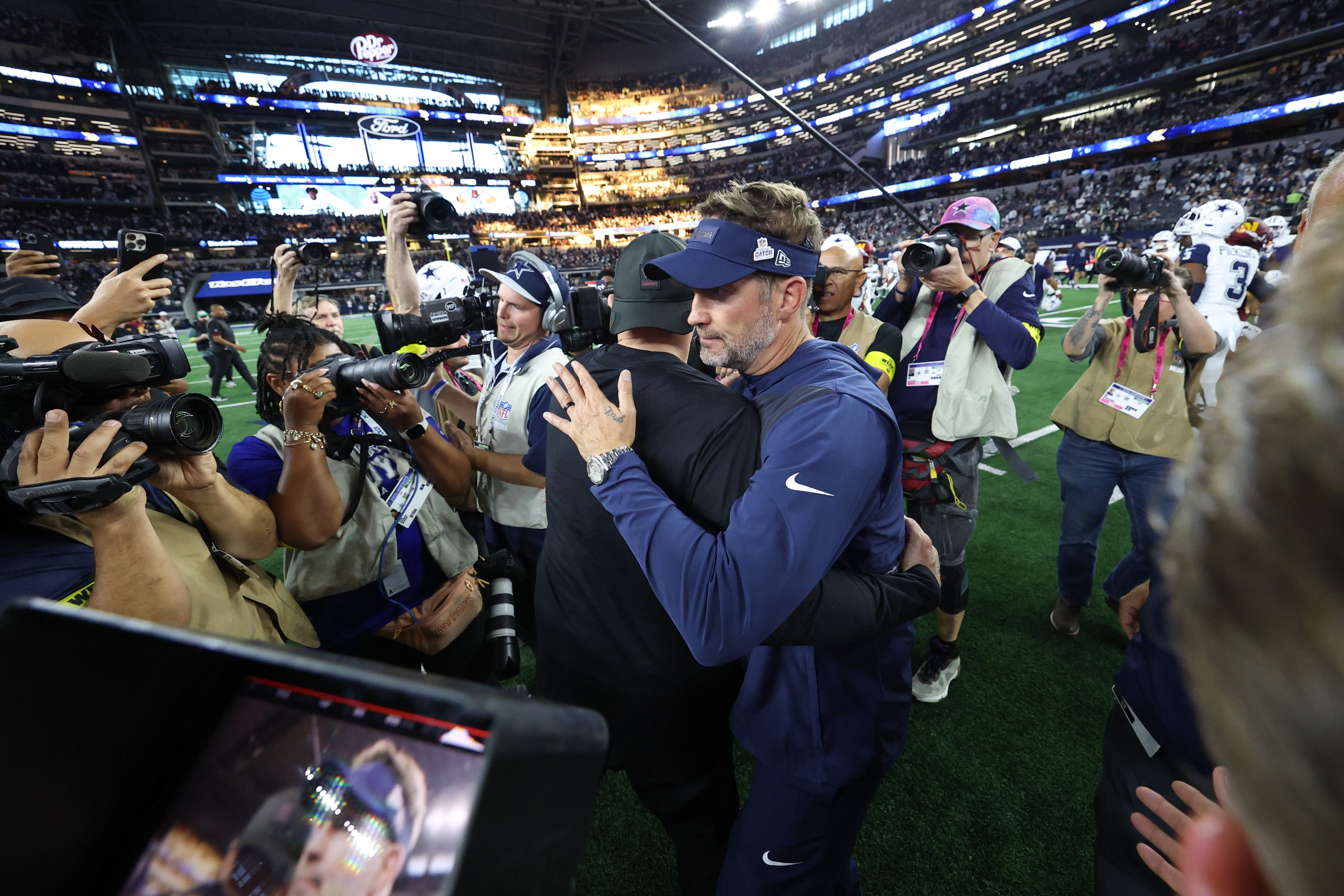 Oct 19, 2025; Arlington, Texas, USA; Washington Commanders head coach Dan Quinn and Dallas Cowboys head coach Brian Schottenheimer hug after the game at AT&T Stadium.
