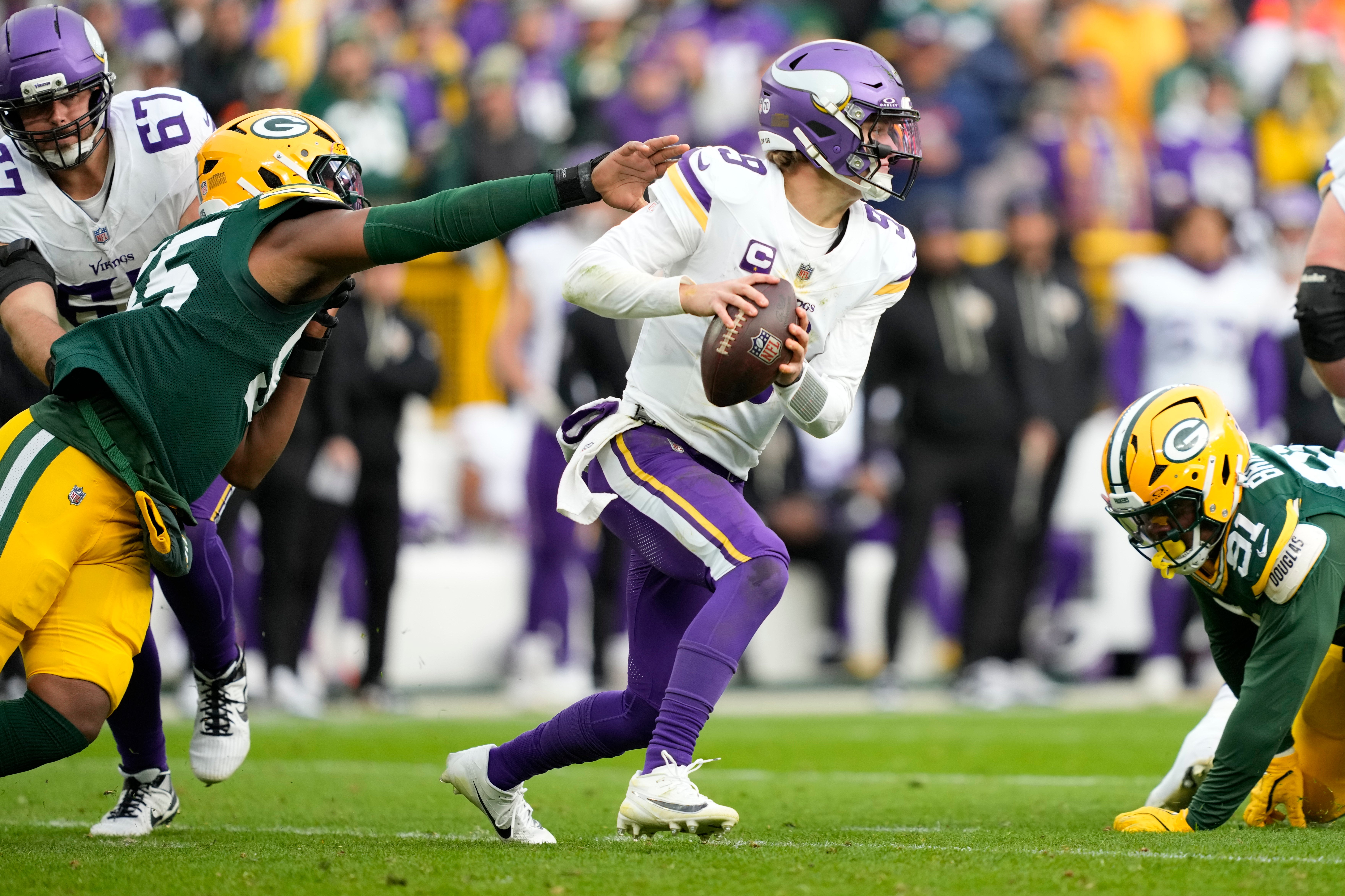 Nov 23, 2025; Green Bay, Wisconsin, USA; Minnesota Vikings quarterback J.J. McCarthy (9) avoids the pressure by. Green Bay Packers defensive end Kingsley Enagbare (55) during the second half at Lambeau Field.