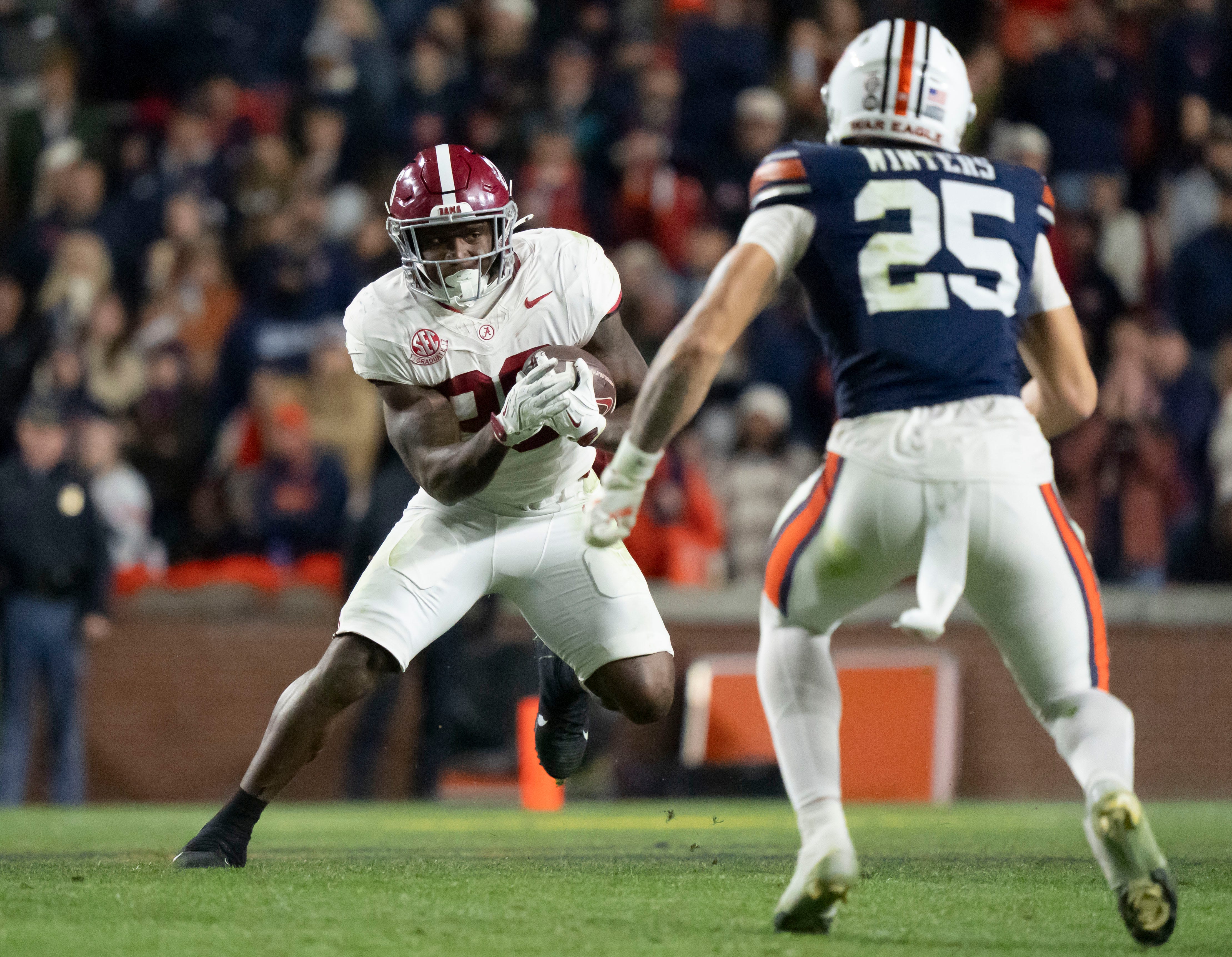 Nov 29, 2025; Auburn, Alabama, USA; Alabama running back Jam Miller (26) cuts back against Auburn safety Eric Winters (25) at Jordan-Hare Stadium. Alabama defeated Auburn 27-20.