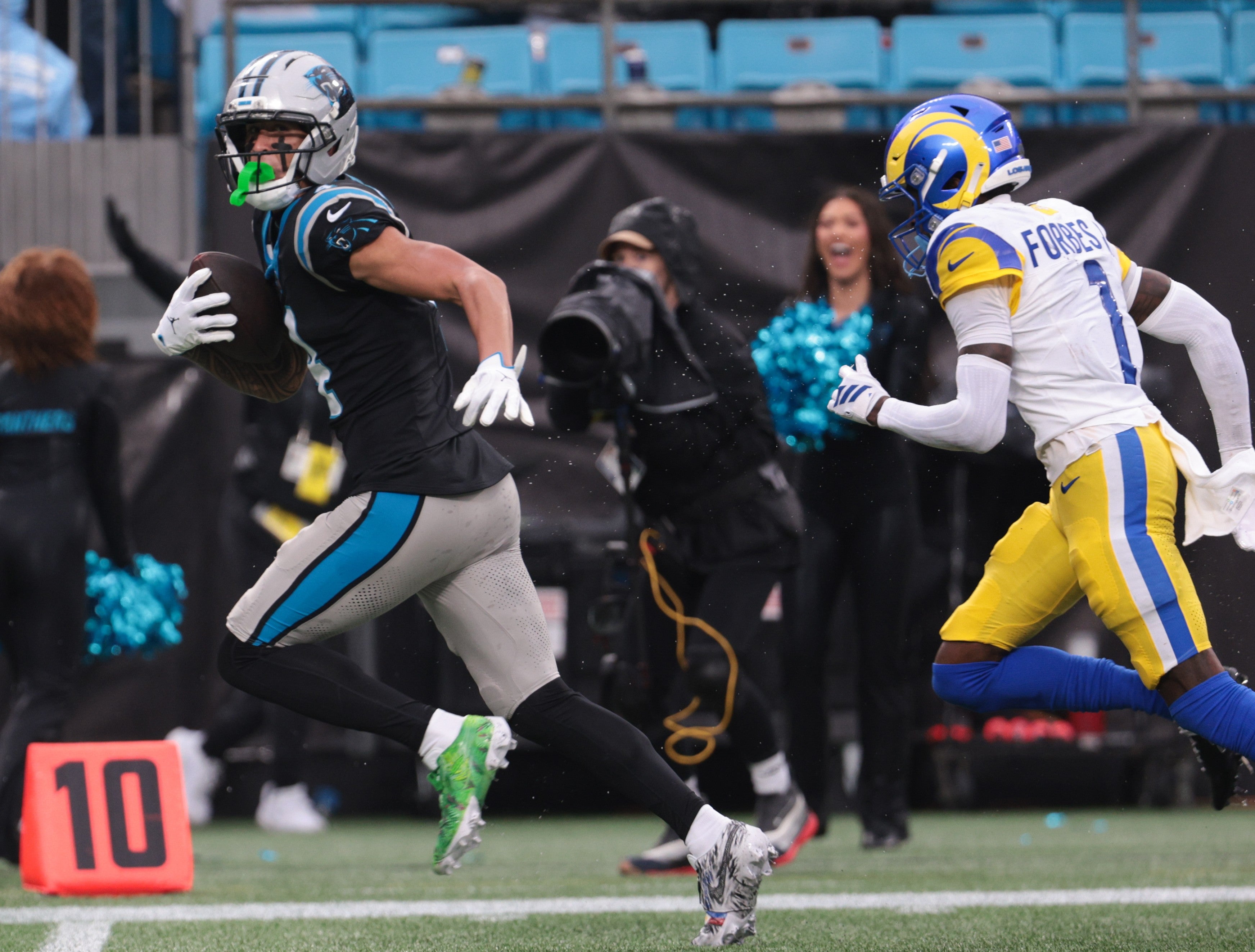 Nov 30, 2025; Charlotte, North Carolina, USA; Carolina Panthers wide receiver Tetairoa McMillan (4) runs after making a catch as Los Angeles Rams cornerback Emmanuel Forbes Jr. (1) defends during the fourth quarter at Bank of America Stadium.
