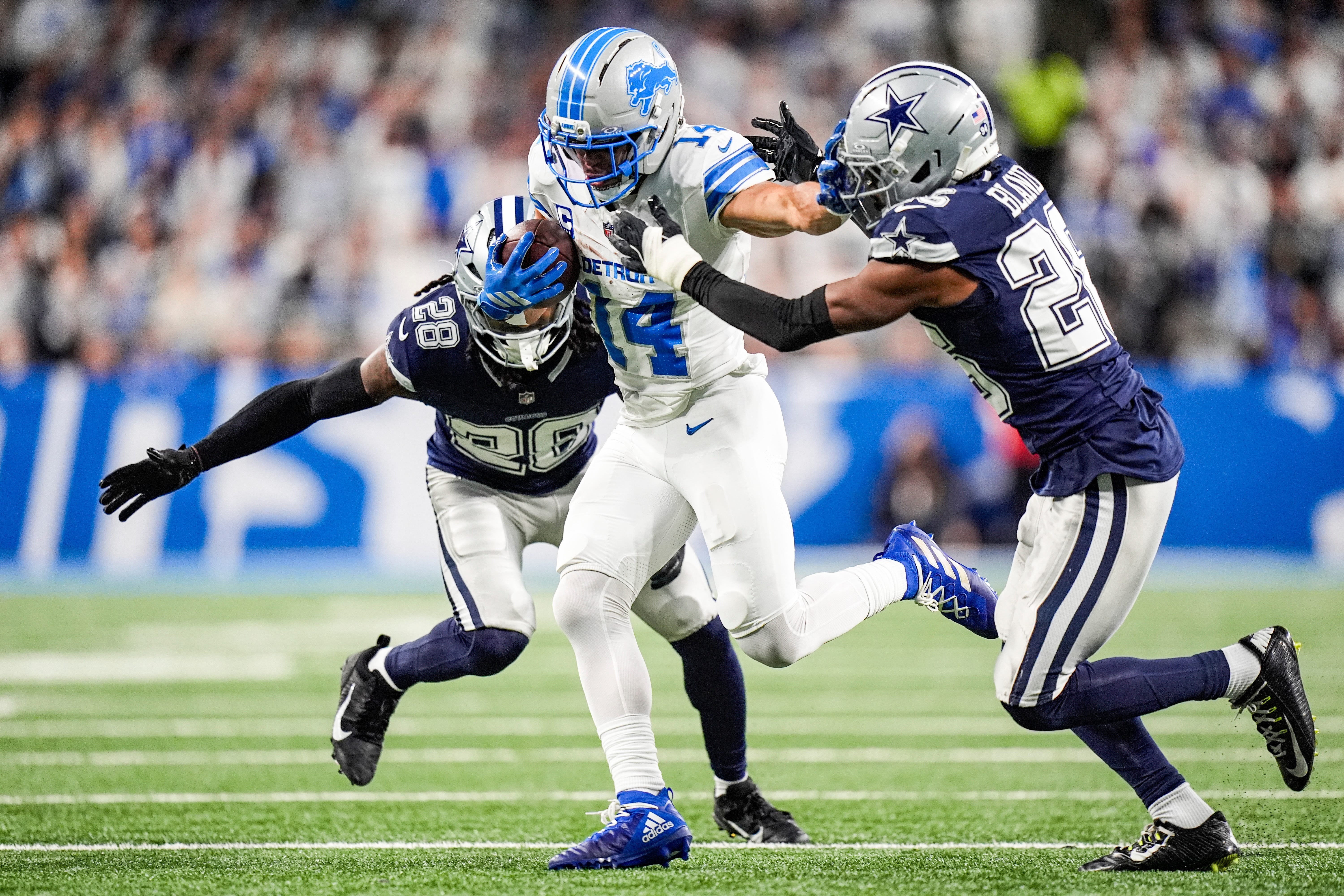 Dec 4, 2025; Detroit, Michigan, USA; Detroit Lions wide receiver Amon-Ra St. Brown (14) makes a catch against Dallas Cowboys safety Malik Hooker (28) and cornerback DaRon Bland (26) during the first half at Ford Field.