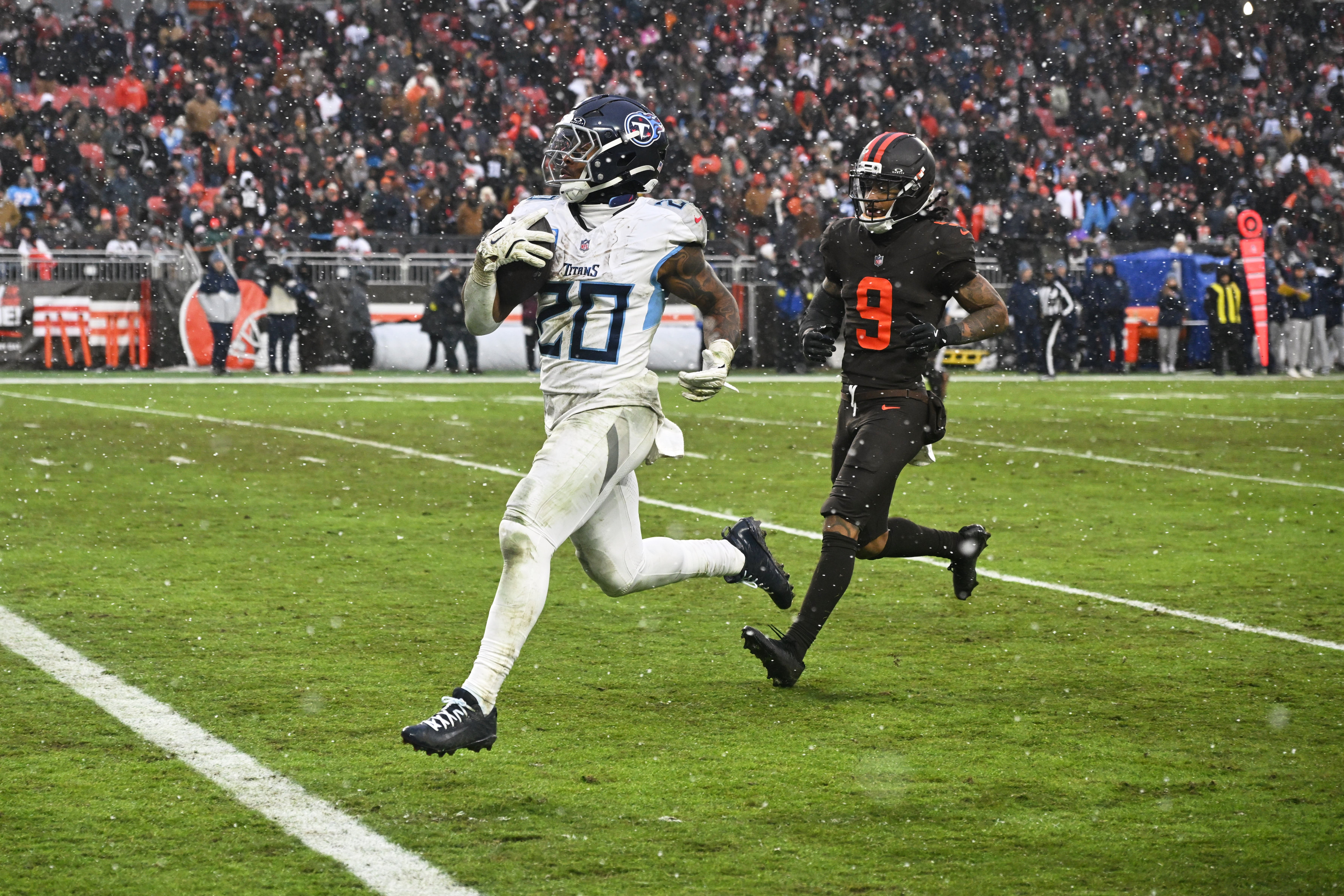 Dec 7, 2025; Cleveland, Ohio, USA; Tennessee Titans running back Tony Pollard (20) runs for a thirty-two yard touchdown against Cleveland Browns safety Grant Delpit (9) during the third quarter at Huntington Bank Field.