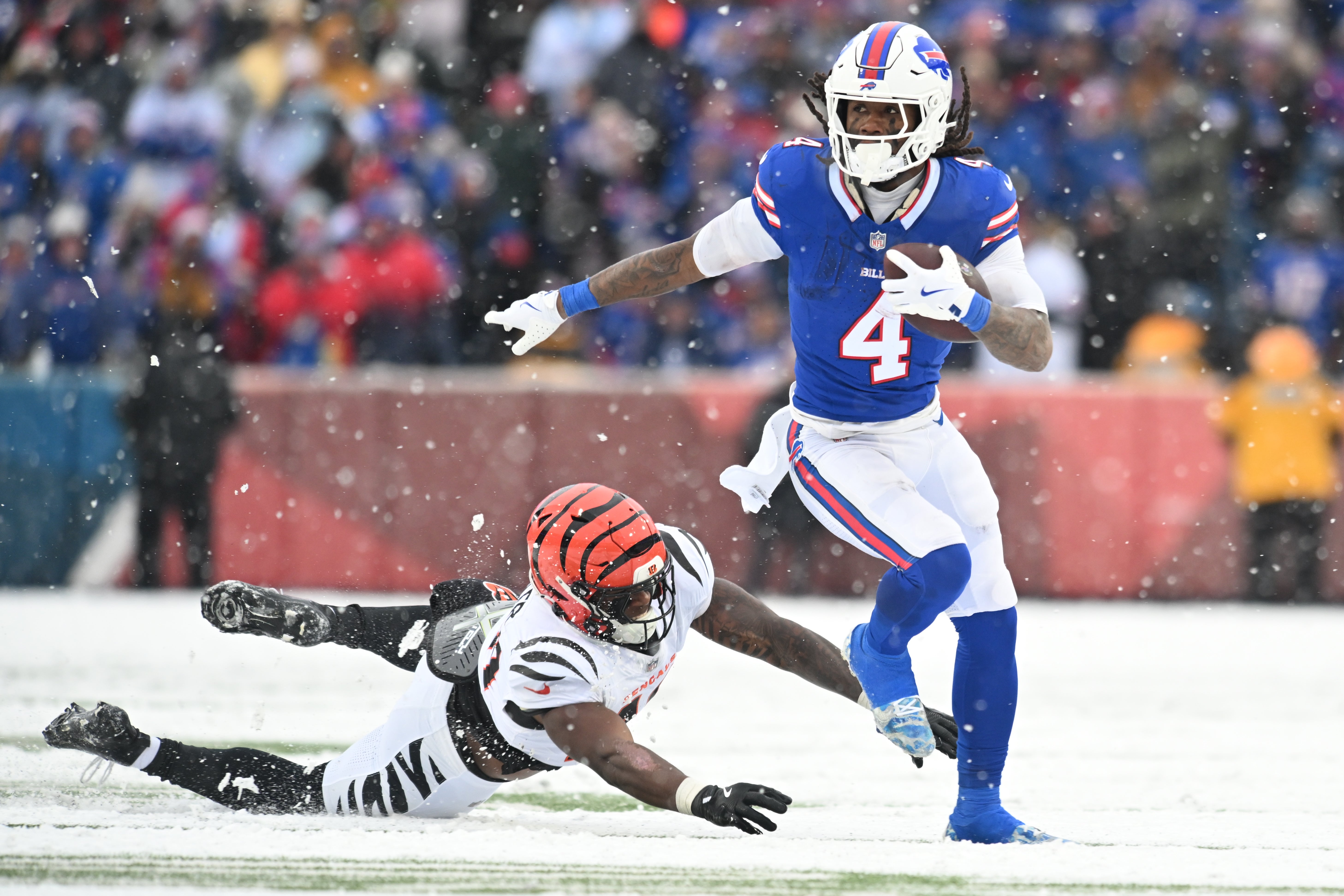 Dec 7, 2025; Orchard Park, New York, USA; Buffalo Bills running back James Cook III (4) runs with the ball while defended by Cincinnati Bengals linebacker Barrett Carter (49) in the second half at Highmark Stadium.