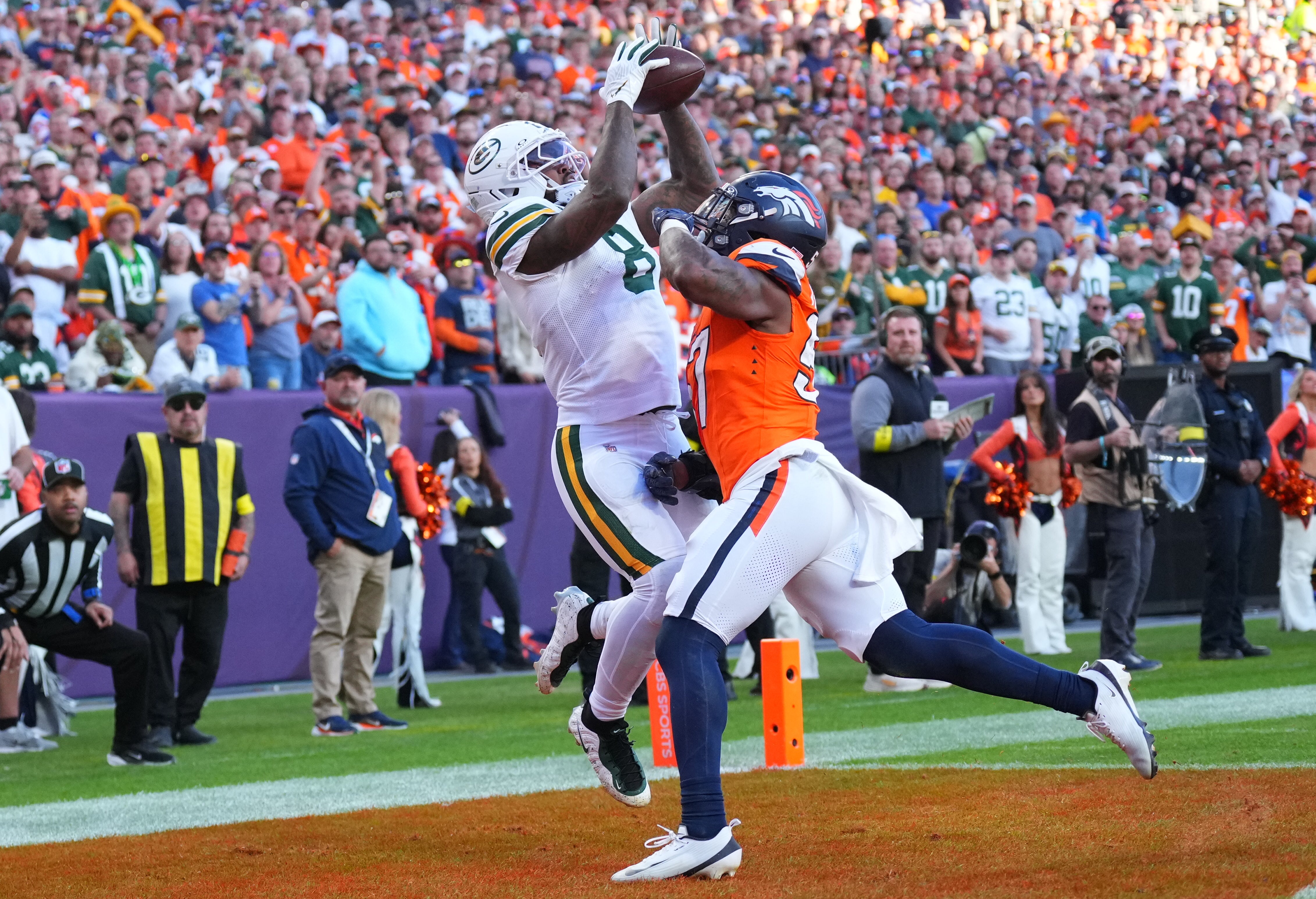 Dec 14, 2025; Denver, Colorado, USA; Green Bay Packers running back Josh Jacobs (8) catches a touchdown pass under pressure from Denver Broncos linebacker Dre Greenlaw (57) during the second quarter at Empower Field at Mile High.