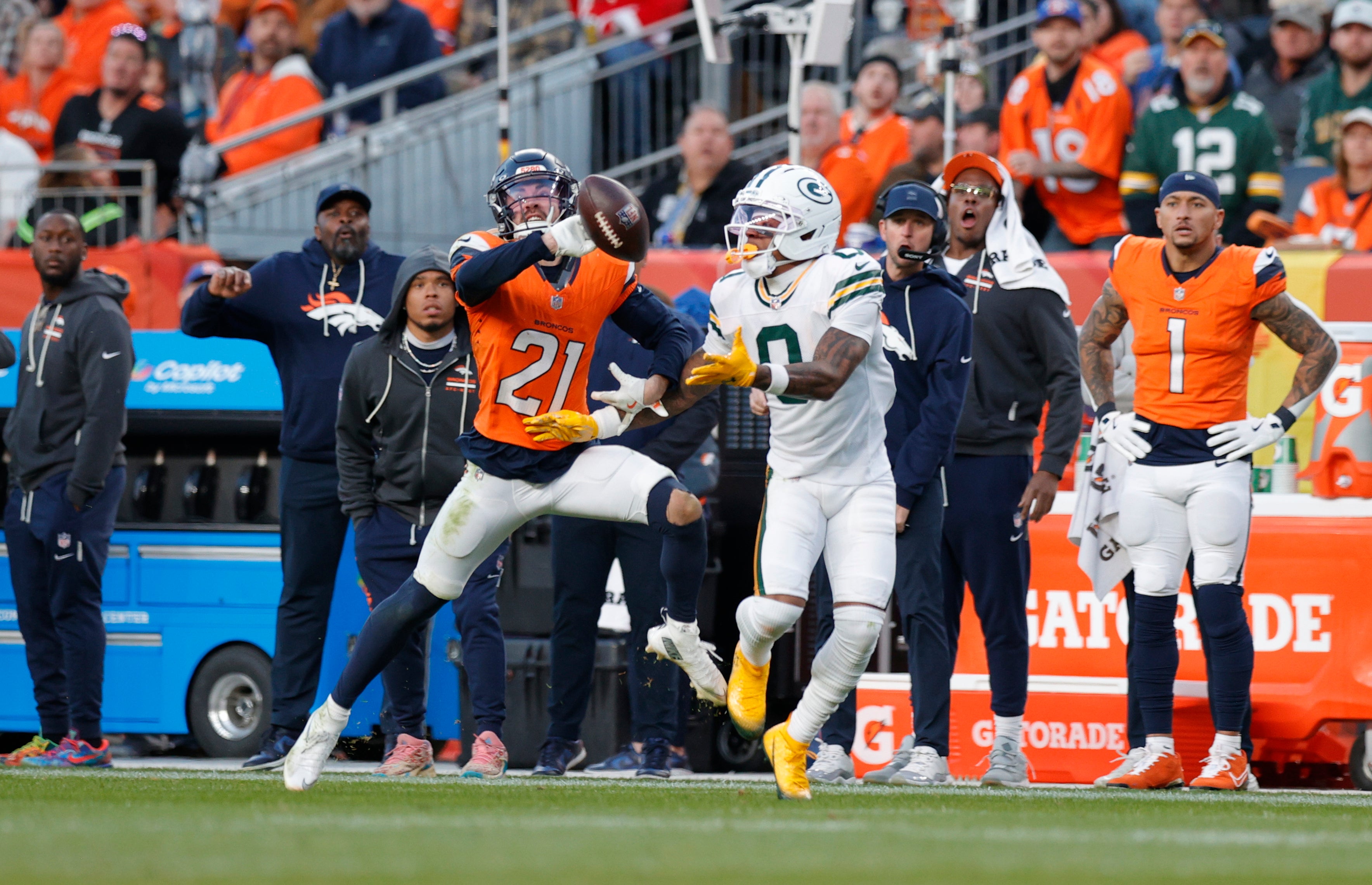 Dec 14, 2025; Denver, Colorado, USA; Green Bay Packers wide receiver Matthew Golden (0) drops a pass as Denver Broncos cornerback Riley Moss (21) defends during the third quarter at Empower Field at Mile High.