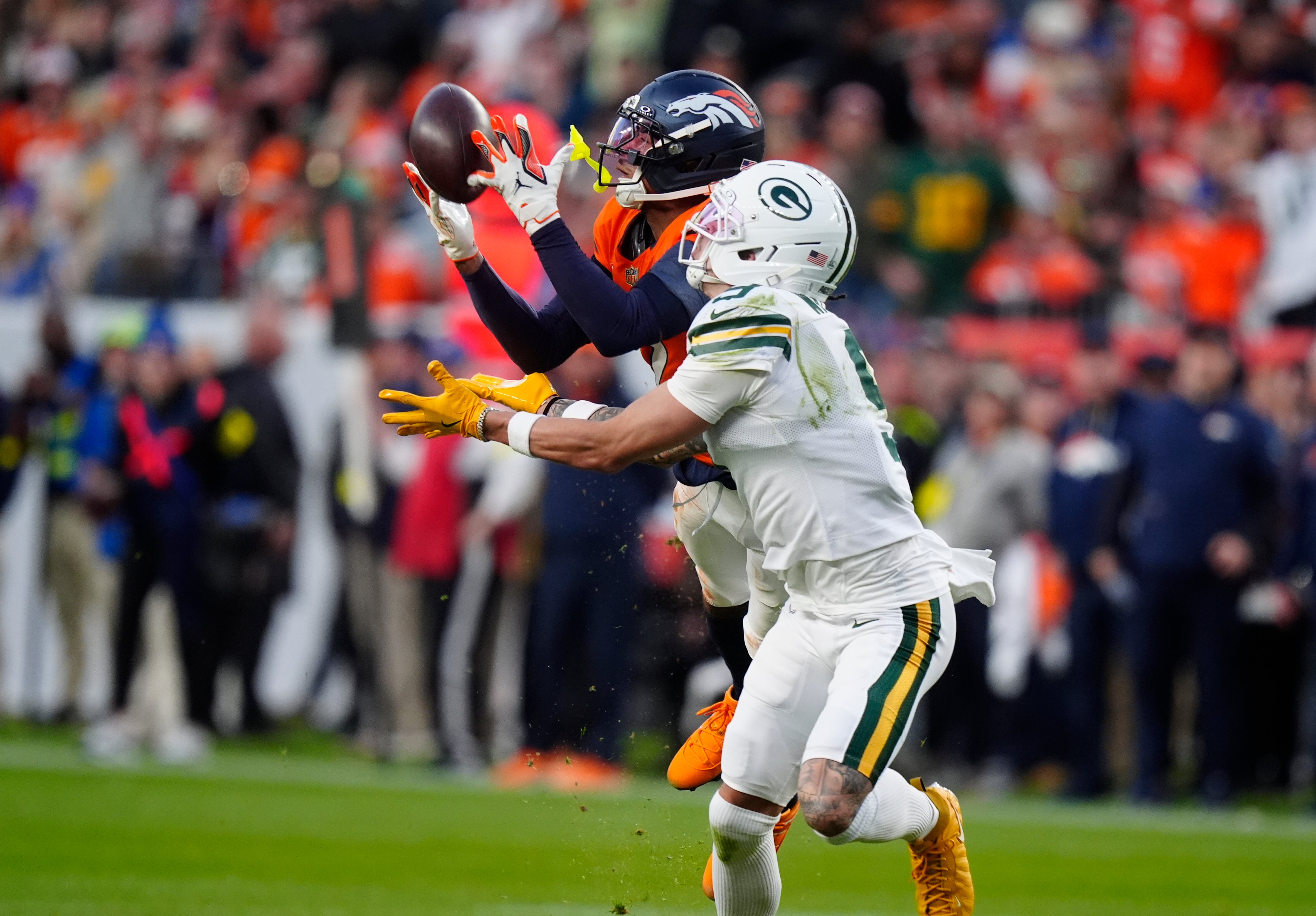 Dec 14, 2025; Denver, Colorado, USA; Denver Broncos cornerback Pat Surtain II (2) catches a pass under pressure from Green Bay Packers wide receiver Christian Watson (9) during the third quarter at Empower Field at Mile High.