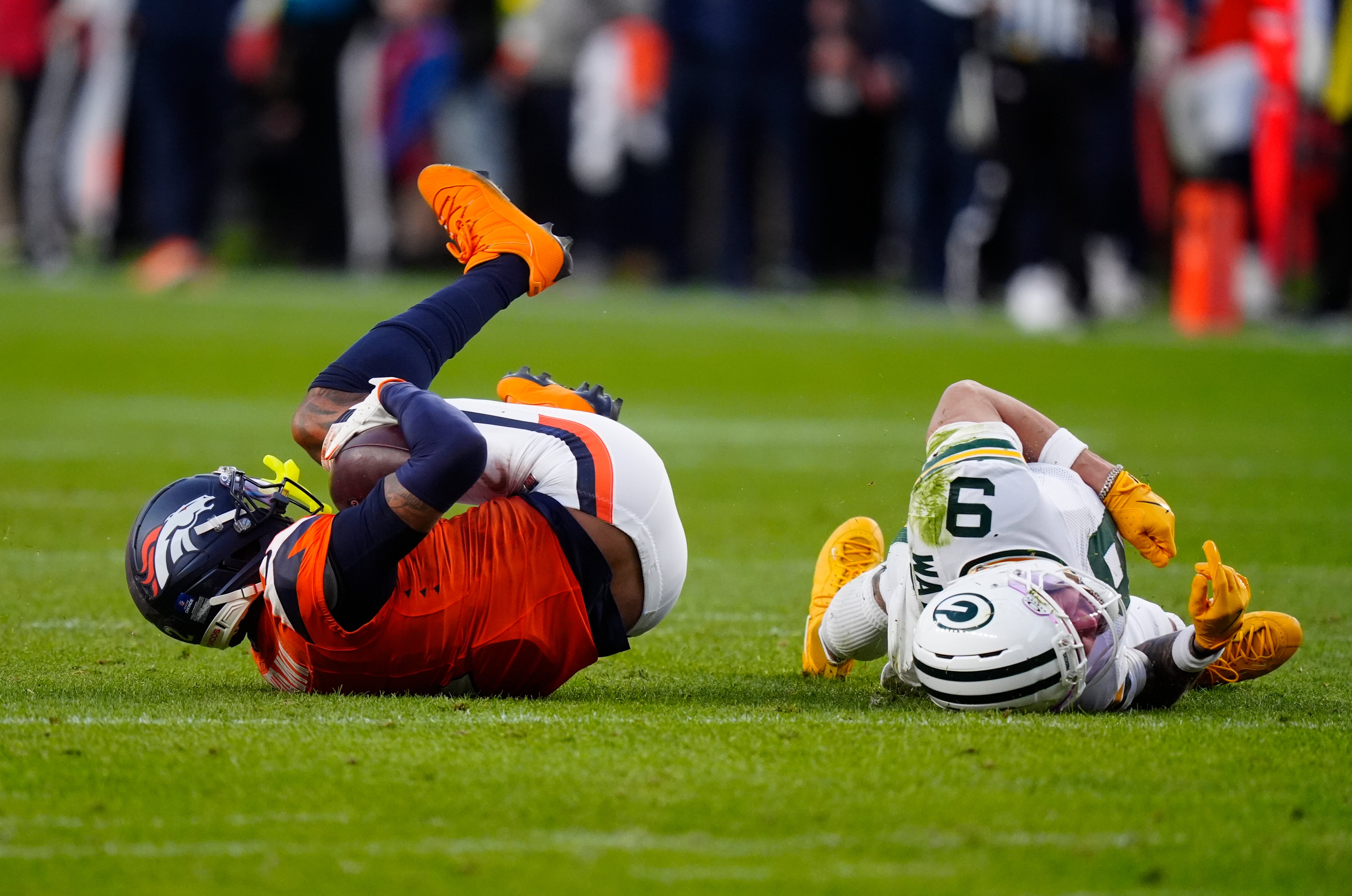 Dec 14, 2025; Denver, Colorado, USA; Denver Broncos cornerback Pat Surtain II (2) makes a catch as Green Bay Packers wide receiver Christian Watson (9) lies on the field following an injury during the third quarter at Empower Field at Mile High.
