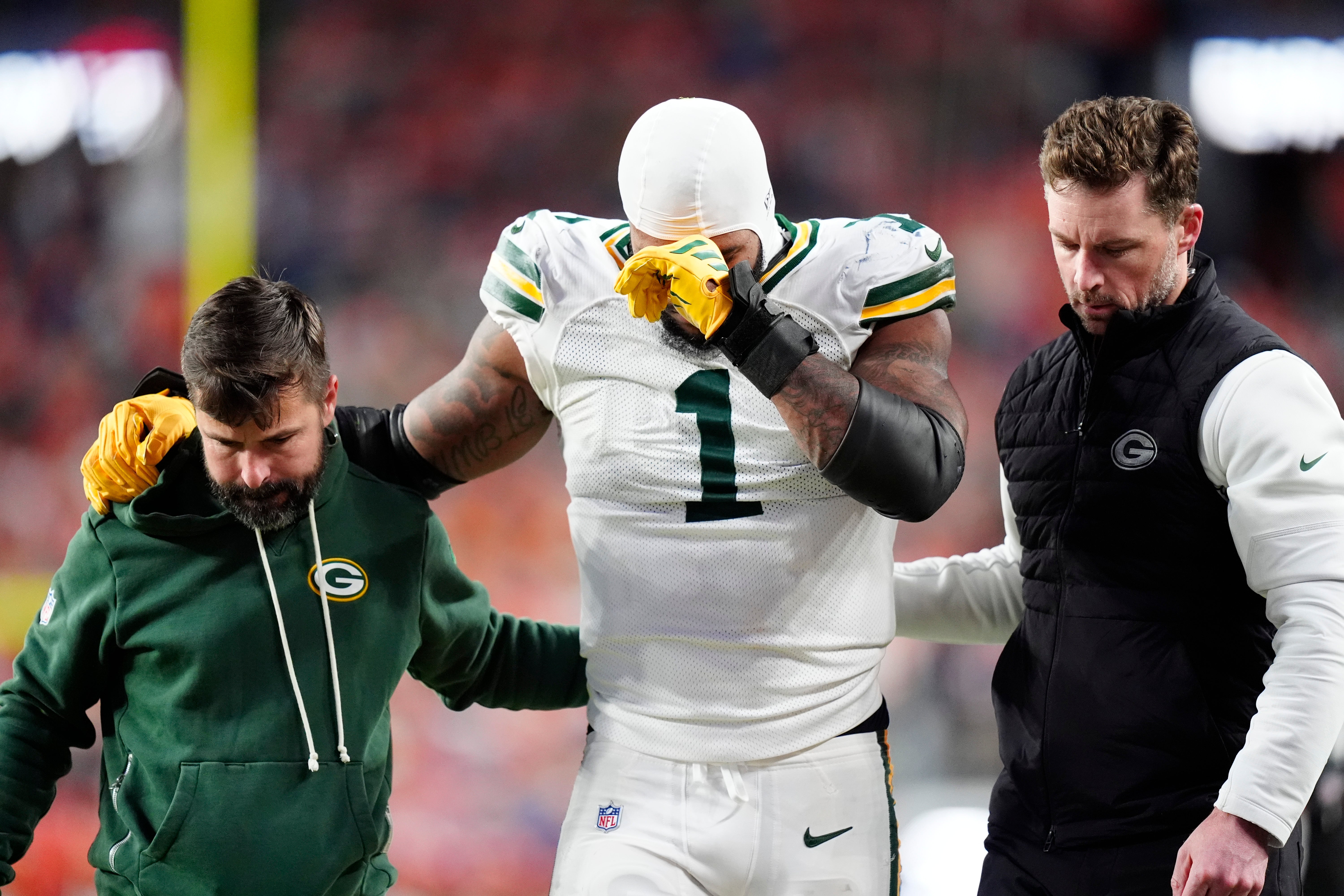 Dec 14, 2025; Denver, Colorado, USA; Green Bay Packers defensive end Micah Parsons (1) walks off the field with help from medical personnel following an injury during the third quarter against the Denver Broncos at Empower Field at Mile High.