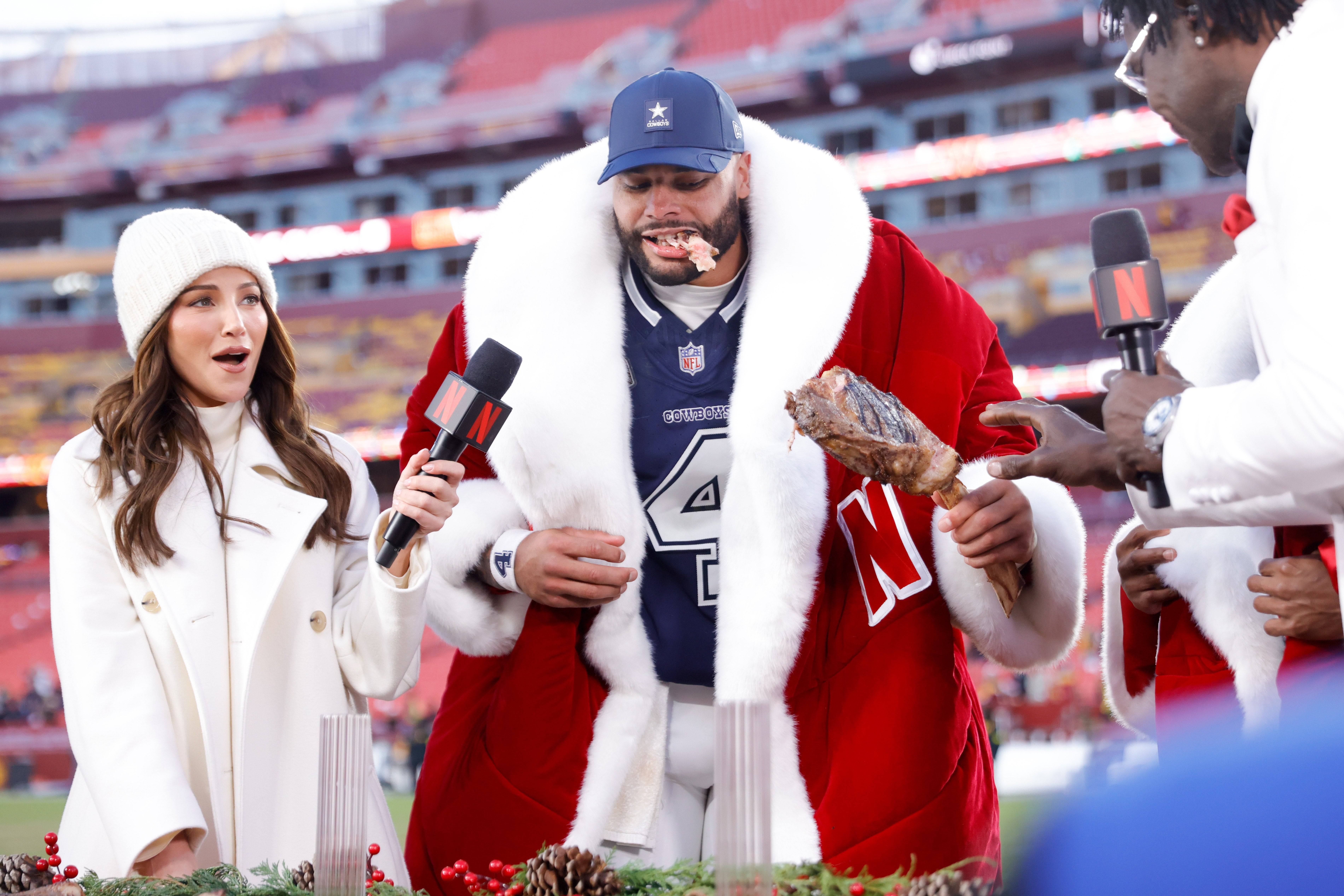 Dec 25, 2025; Landover, Maryland, USA; Dallas Cowboys quarterback Dak Prescott (4) eats a steak as Kay Adams reacts after the game against the Washington Commanders at Northwest Stadium.