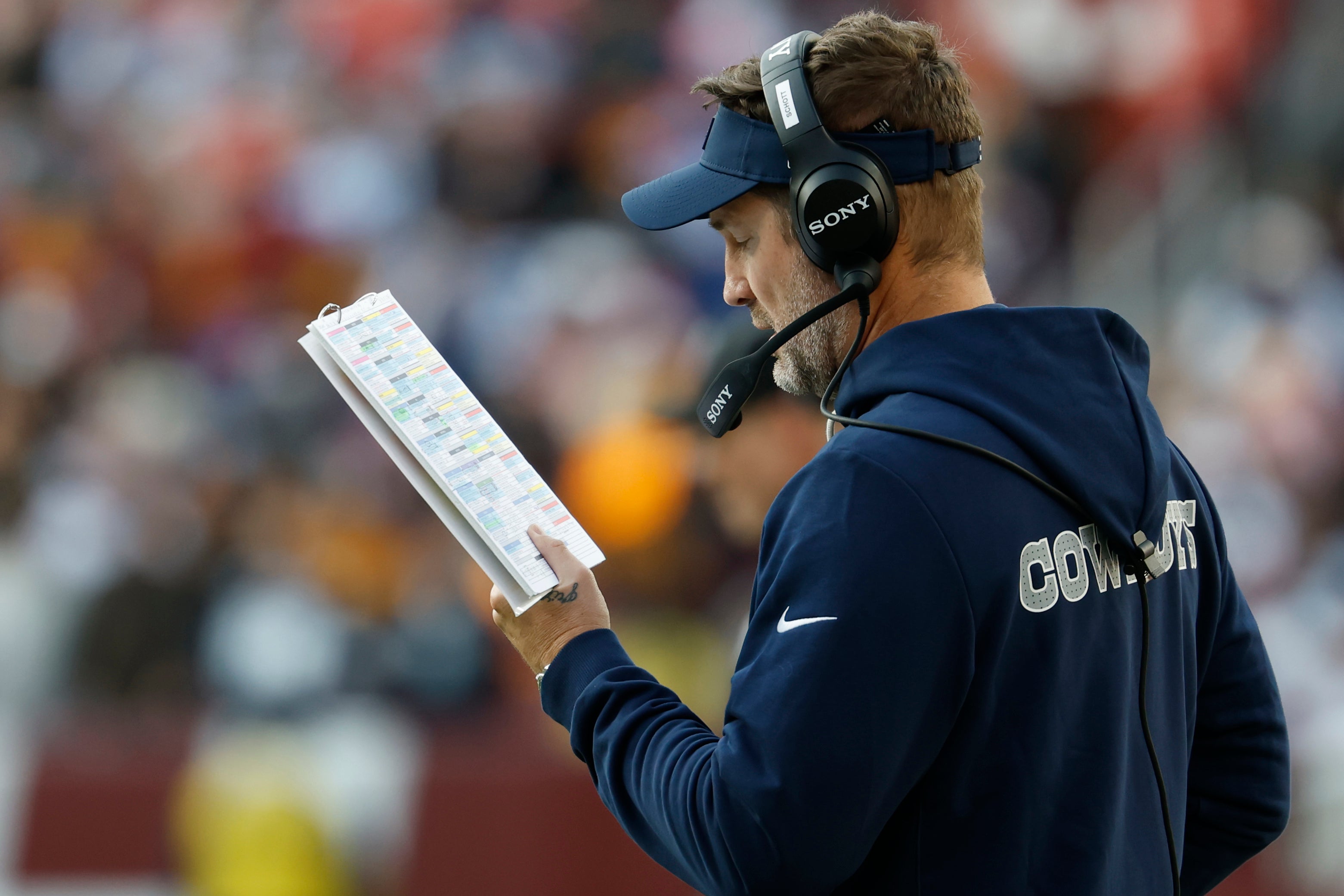 Dec 25, 2025; Landover, Maryland, USA; Dallas Cowboys head coach Brian Schottenheimer looks at his play sheet on the sidelines against the Washington Commanders during the second half at Northwest Stadium.