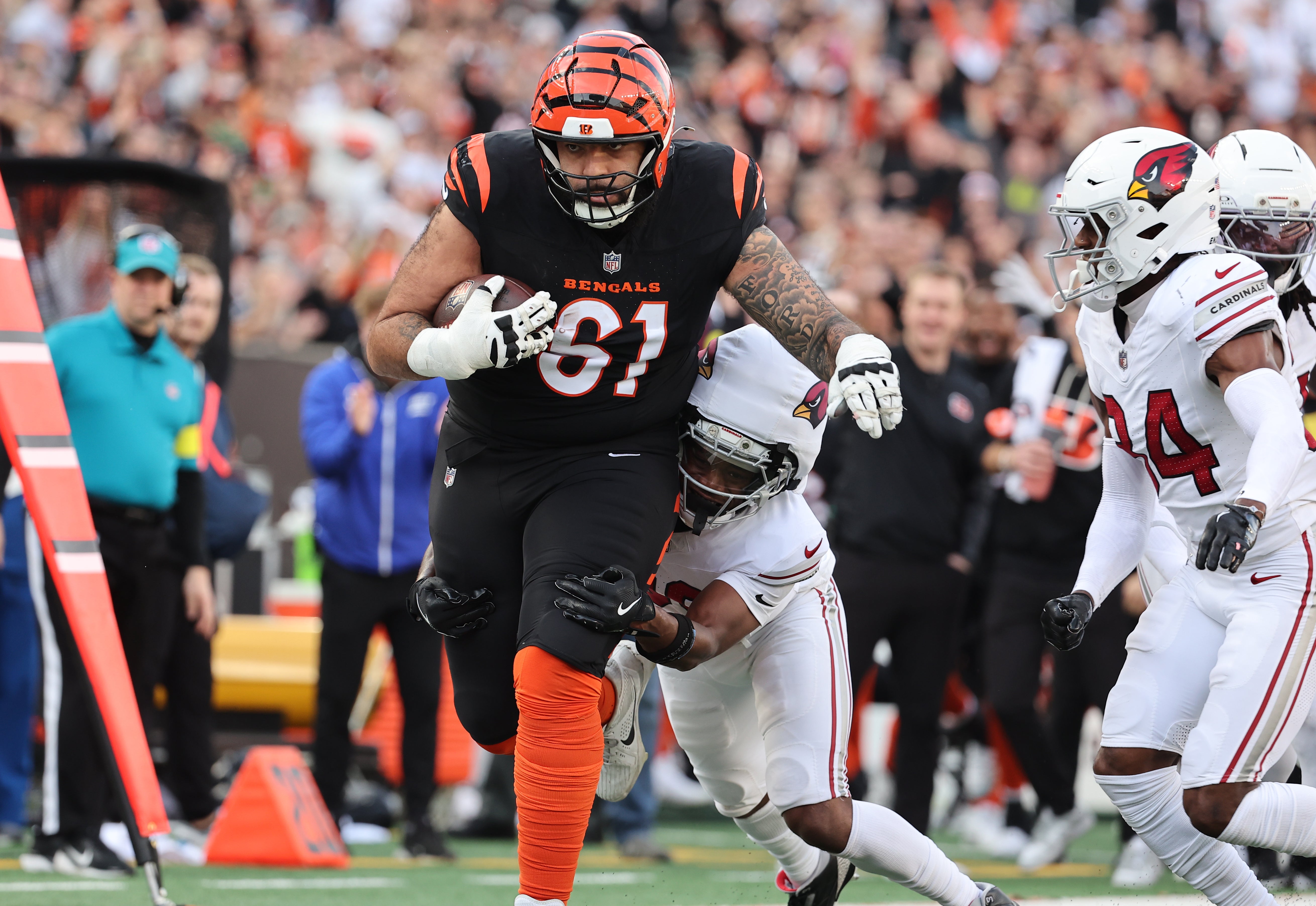 Dec 28, 2025; Cincinnati, Ohio, USA; Cincinnati Bengals guard Cody Ford (61) runs against Arizona Cardinals cornerback Darren Hall (30) and safety Jalen Thompson (34) during the second half at Paycor Stadium.