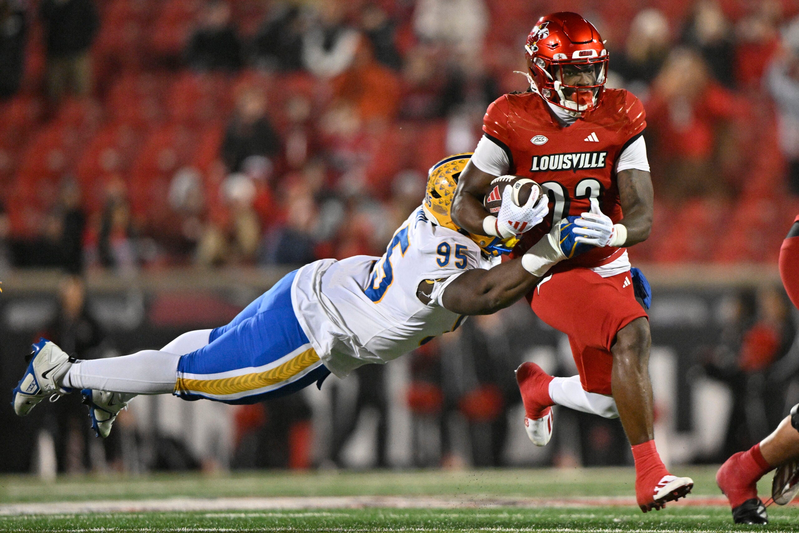 Nov 23, 2024; Louisville, Kentucky, USA; Louisville Cardinals running back Keyjuan Brown (22) runs against Pittsburgh Panthers defensive lineman Francis Brewu (95) during the second half at L&N Federal Credit Union Stadium. Louisville defeated Pittsburgh 37-9. Mandatory Credit: Jamie Rhodes-Imagn Images