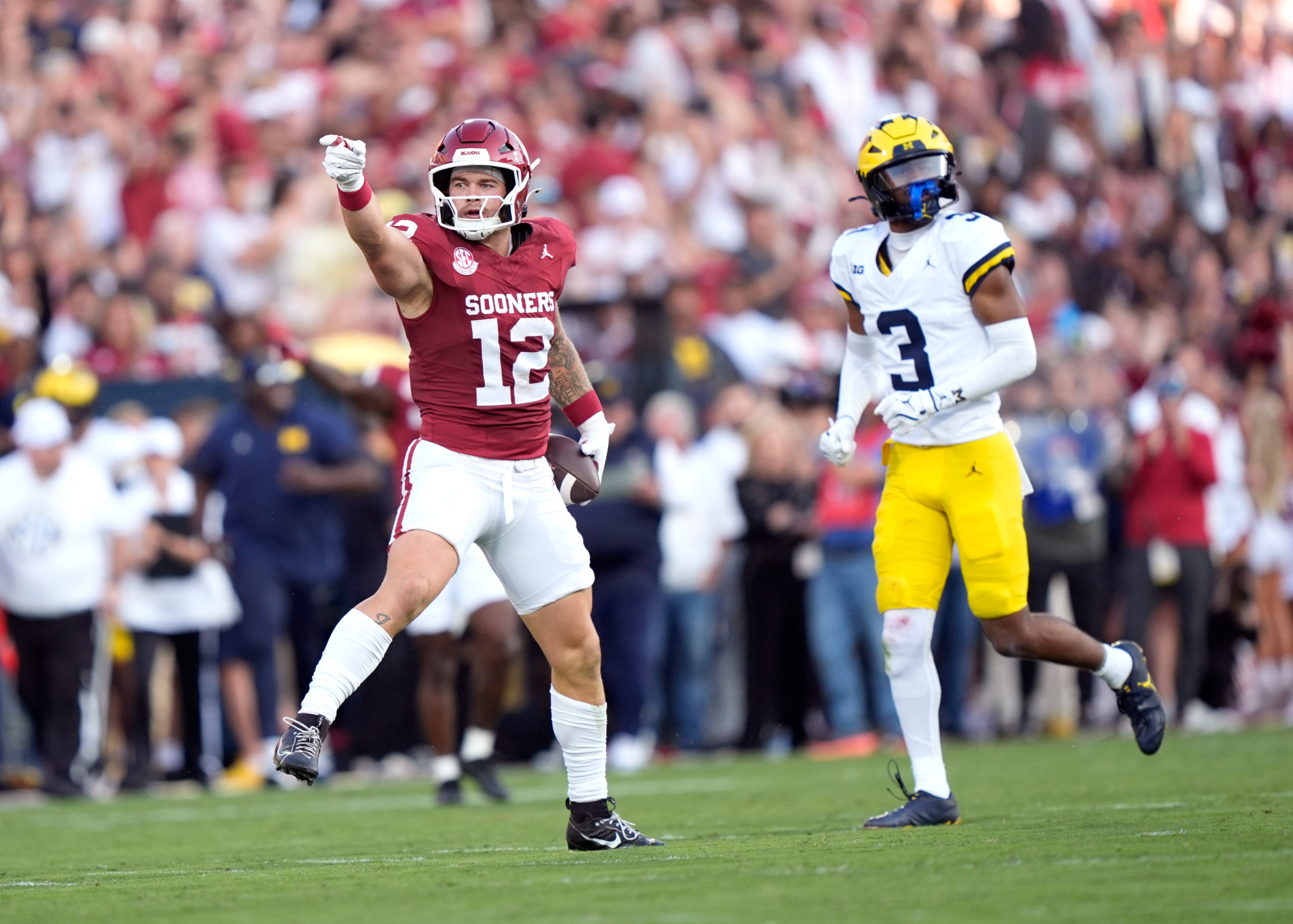 Oklahoma's Jaren Kanak (12) celebrates in front of Michigan's Jaden Mangham (3) in the first half of the college football game between the University of Oklahoma Sooner and the University of Michigan Wolverines at the Gaylord Family Ð Oklahoma Memorial Stadium in Norman, Okla., Saturday, Sept. 6, 2025.