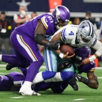 Dec 14, 2025; Arlington, Texas, USA; Dallas Cowboys quarterback Dak Prescott (4) is tackled by Minnesota Vikings defensive tackle Jalen Redmond (61) during the first half at AT&T Stadium.