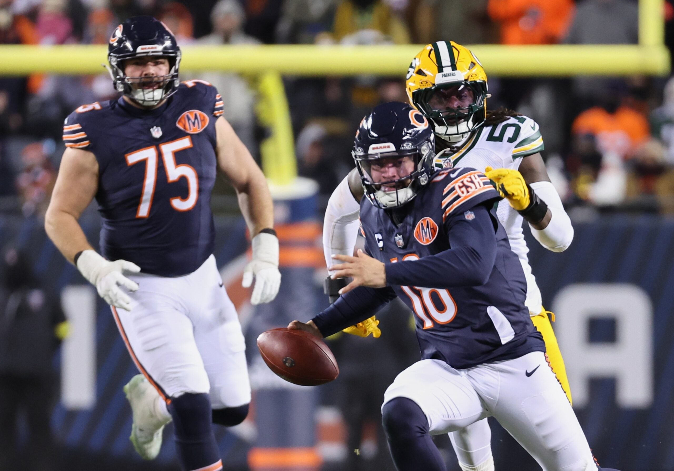 Dec 20, 2025; Chicago, Illinois, USA; Chicago Bears quarterback Caleb Williams (18) runs with the ball and offensive tackle Ozzy Trapilo (75) watches the play against Green Bay Packers defensive end Brenton Cox Jr. (57) during overtime at Soldier Field.
