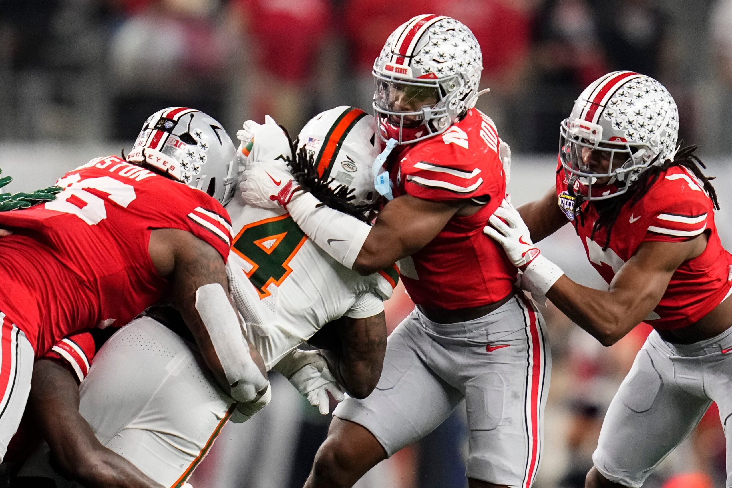 Ohio State Buckeyes defensive back Caleb Downs (2) and defensive end Eddrick Houston (96) tackle Miami Hurricanes running back Mark Fletcher Jr. (4) during the Cotton Bowl at AT&T Stadium in Arlington, Texas for the College Football Playoff quarterfinal game on Dec. 31, 2025. Ohio State lost 24-14.