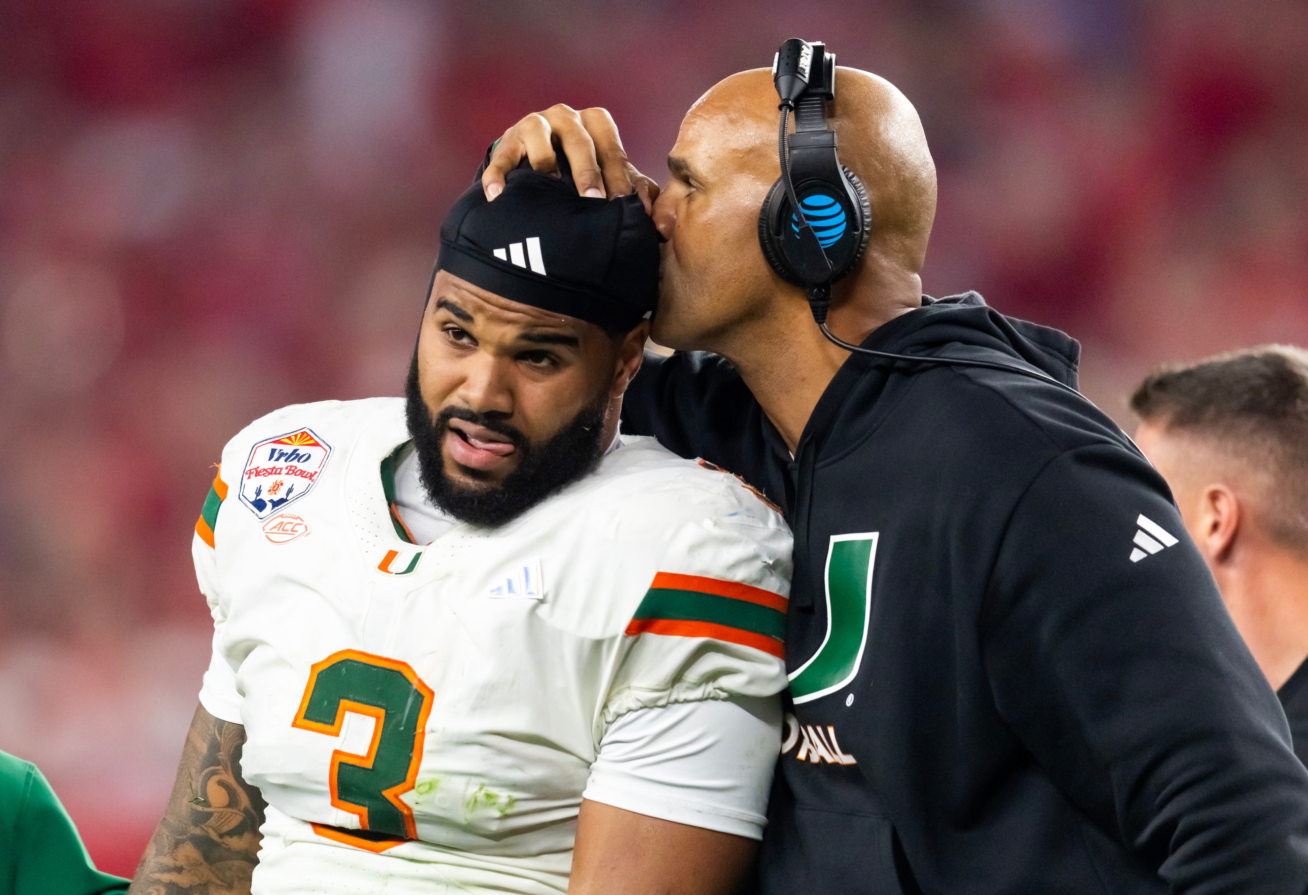 Jan 8, 2026; Glendale, AZ, USA; Miami Hurricanes defensive line coach Jason Taylor kisses the head of defensive lineman Akheem Mesidor (3) after suffering an injury against the Mississippi Rebels during the 2026 Fiesta Bowl and semifinal game of the College Football Playoff at State Farm Stadium.