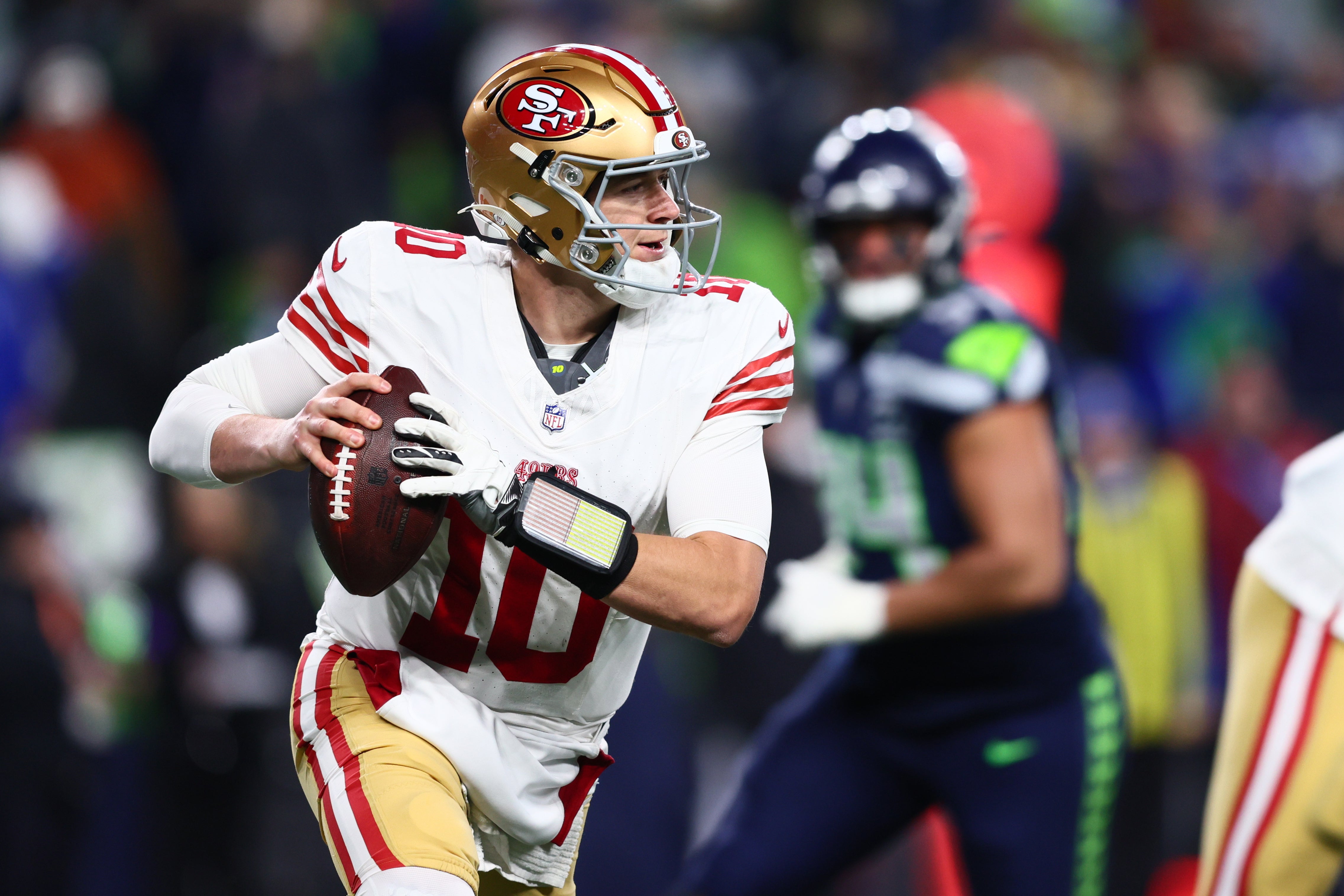 Jan 17, 2026; Seattle, WA, USA; San Francisco 49ers quarterback Mac Jones (10) rolls out against the Seattle Seahawks during the second half in an NFC Divisional Round game at Lumen Field.