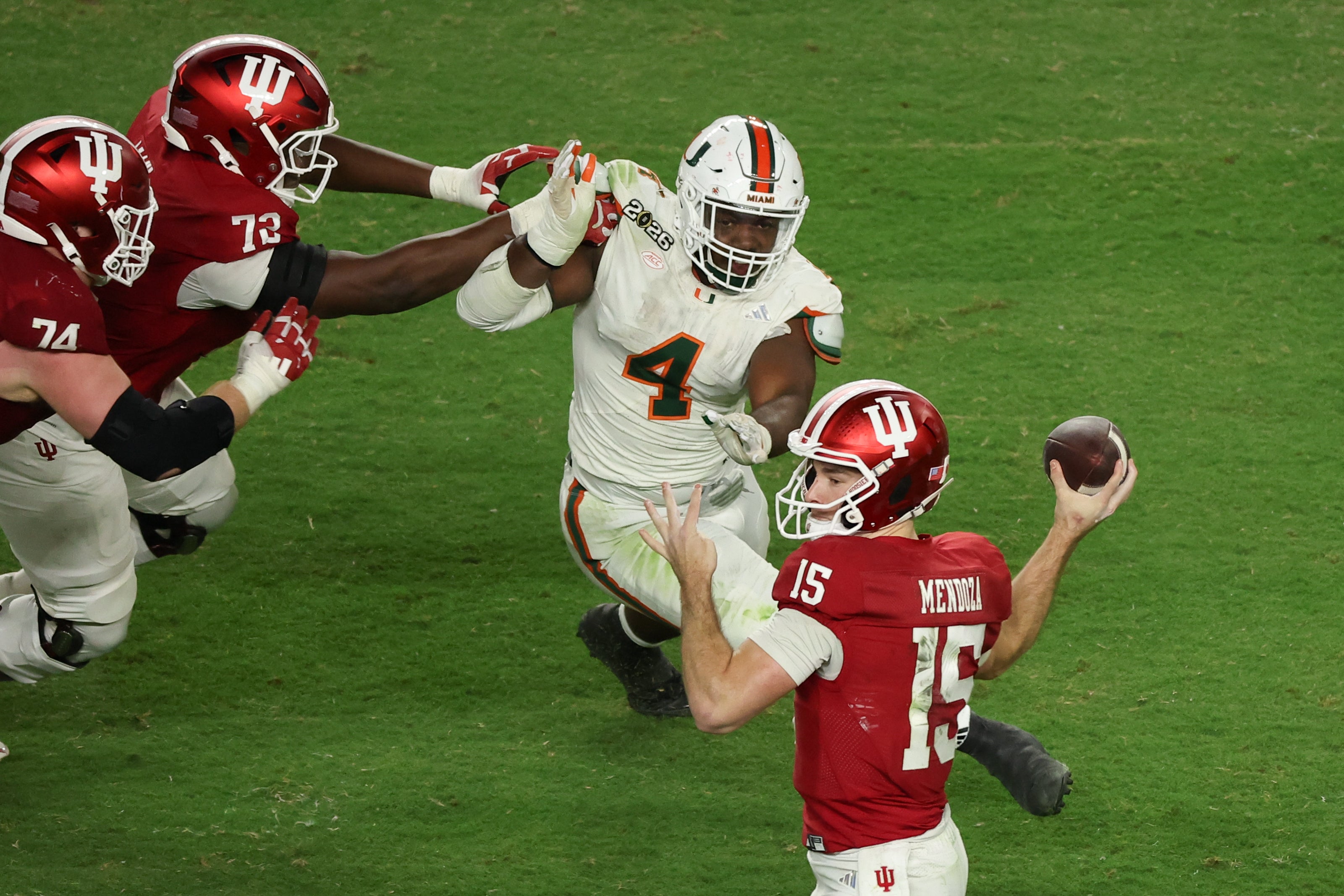 Jan 19, 2026; Miami Gardens, FL, USA; Indiana Hoosiers quarterback Fernando Mendoza (15) passes the ball under pressure by Miami Hurricanes defensive lineman Rueben Bain Jr. (4) in the third quarter during the College Football Playoff National Championship game at Hard Rock Stadium.