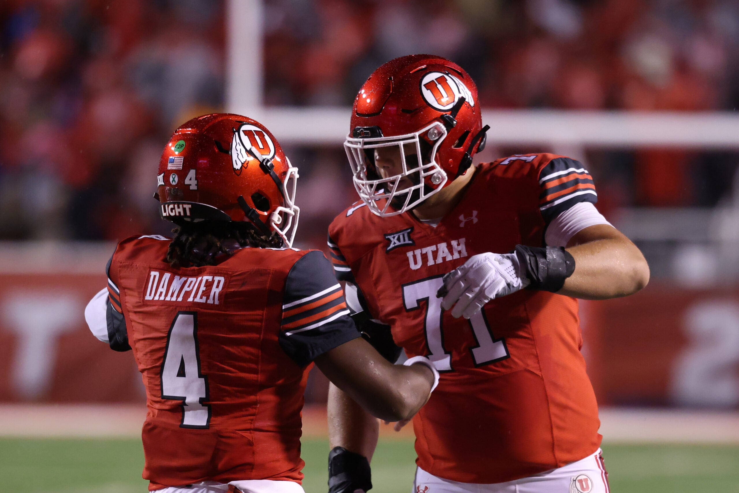Oct 11, 2025; Salt Lake City, Utah, USA; Utah Utes quarterback Devon Dampier (4) celebrates scoring a touchdown against the Arizona State Sun Devils with Utah Utes offensive lineman Caleb Lomu (71) during the second quarter at Rice-Eccles Stadium.