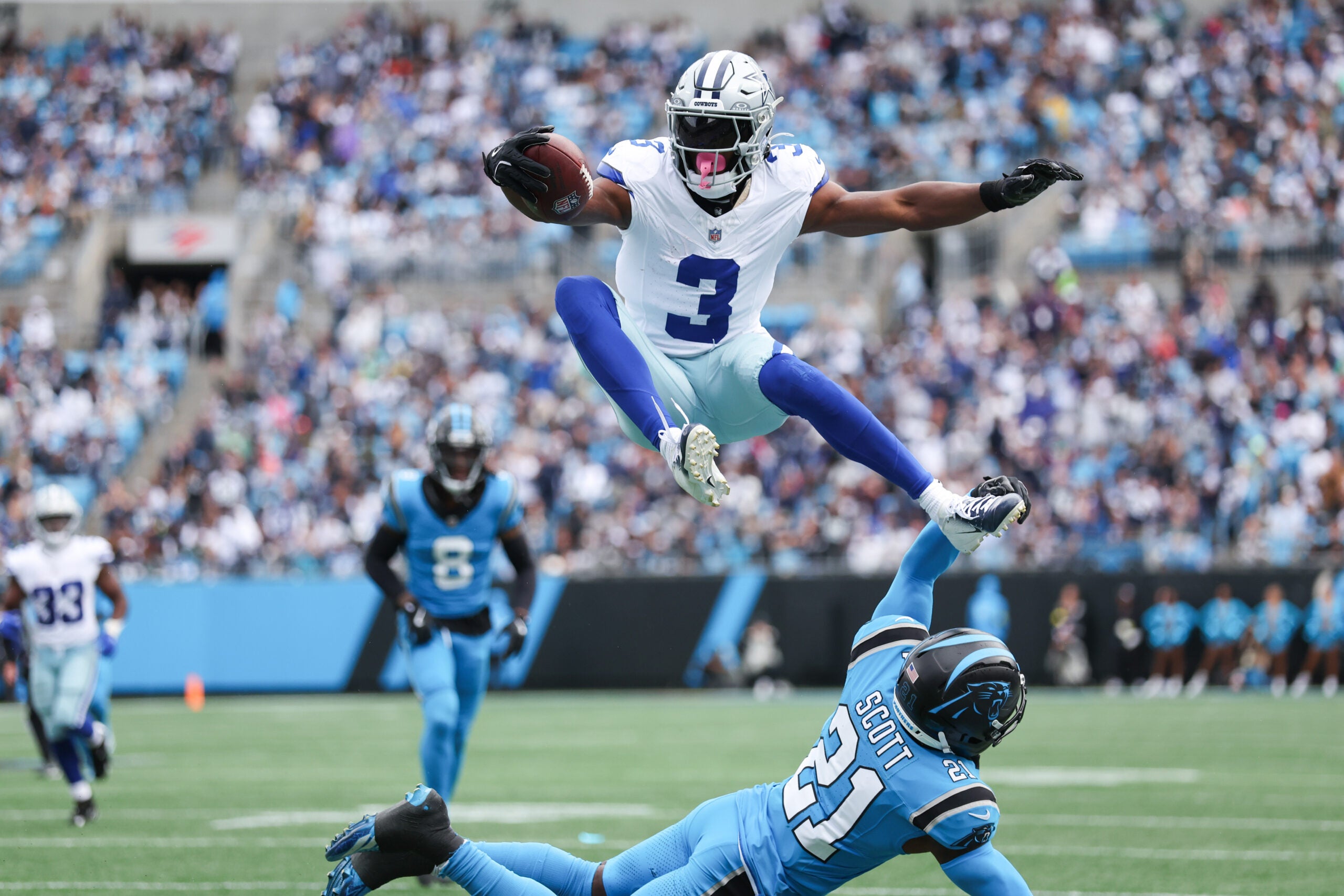 Oct 12, 2025; Charlotte, North Carolina, USA; Dallas Cowboys wide receiver George Pickens (3) jumps over Carolina Panthers safety Nick Scott (21) during the first quarter against the Carolina Panthers at Bank of America Stadium.