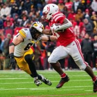 Nov 28, 2025; Lincoln, Nebraska, USA; Nebraska Cornhuskers running back Emmett Johnson (21) runs against Iowa Hawkeyes defensive back Zach Lutmer (6) during the third quarter at Memorial Stadium. Mandatory Credit: Dylan Widger-Imagn Images
