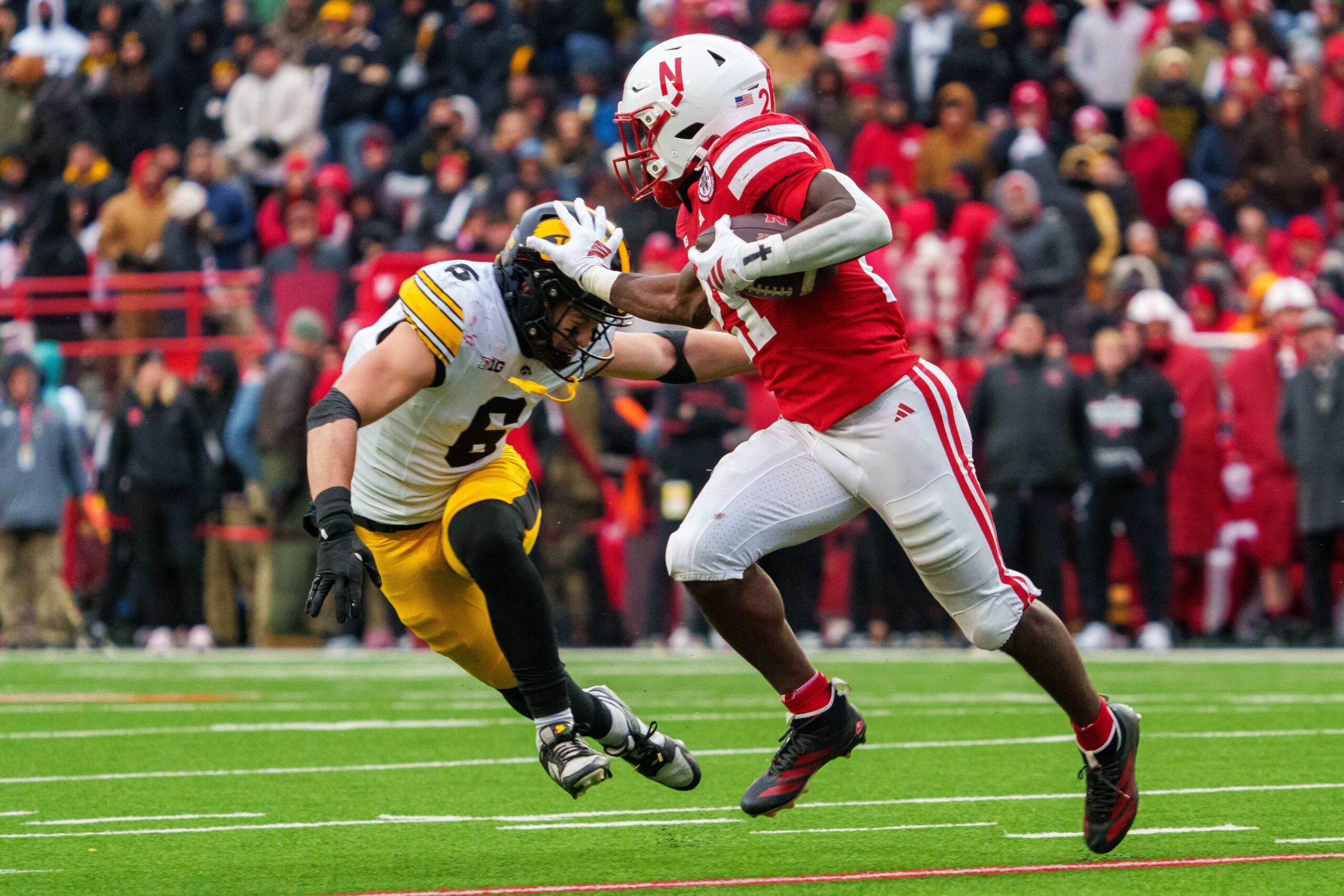 Nov 28, 2025; Lincoln, Nebraska, USA; Nebraska Cornhuskers running back Emmett Johnson (21) runs against Iowa Hawkeyes defensive back Zach Lutmer (6) during the third quarter at Memorial Stadium. Mandatory Credit: Dylan Widger-Imagn Images