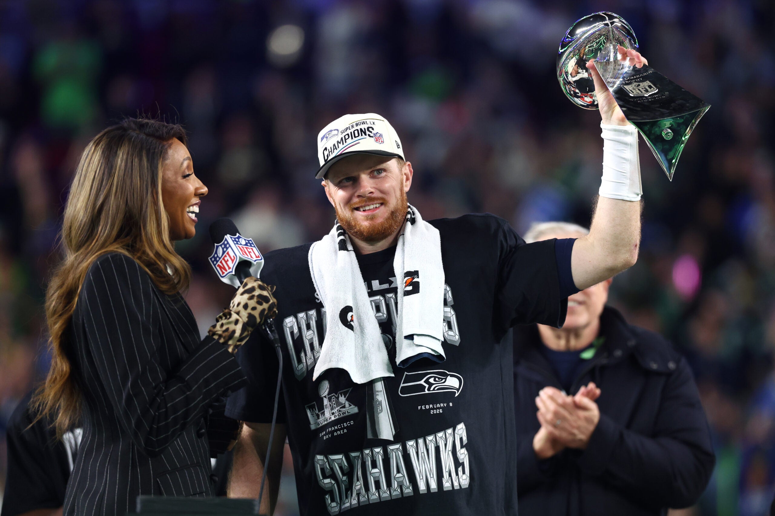 Feb 8, 2026; Santa Clara, CA, USA; Seattle Seahawks quarterback Sam Darnold (14) celebrates with the Vince Lombardi trophy on the podium after defeating the New England Patriots in Super Bowl LX at Levi's Stadium.