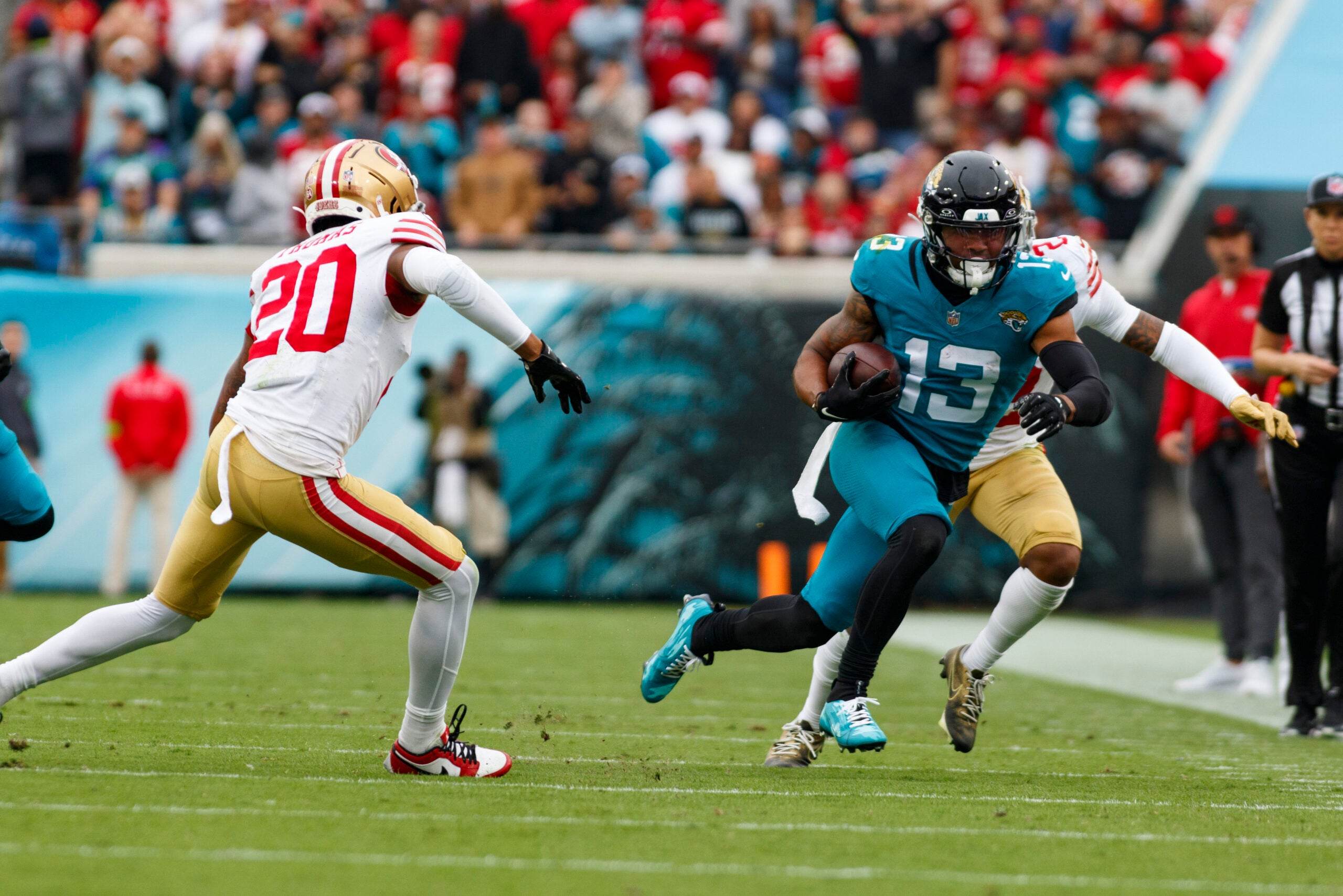 Nov 12, 2023; Jacksonville, Florida, USA; Jacksonville Jaguars wide receiver Christian Kirk (13) runs with the ball past San Francisco 49ers cornerback Ambry Thomas (20) during the second quarter at EverBank Stadium.