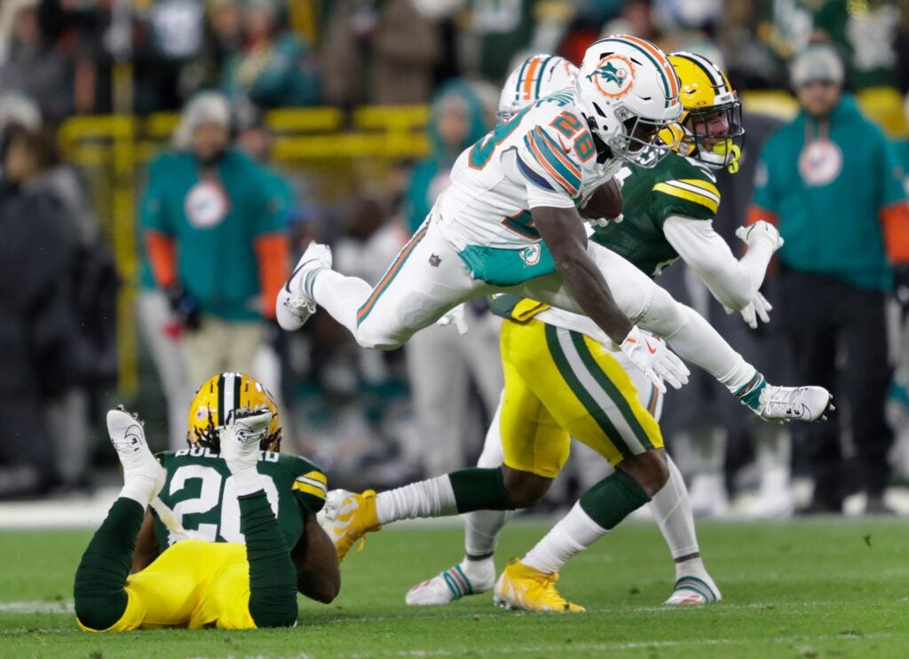 Miami Dolphins running back De'Von Achane (28) leaps over Green Bay Packers safety Javon Bullard (20) for a first down reception during their football game Thursday, November 28, 2024, at Lambeau Field in Green Bay, Wisconsin.