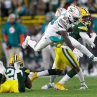 Miami Dolphins running back De'Von Achane (28) leaps over Green Bay Packers safety Javon Bullard (20) for a first down reception during their football game Thursday, November 28, 2024, at Lambeau Field in Green Bay, Wisconsin.