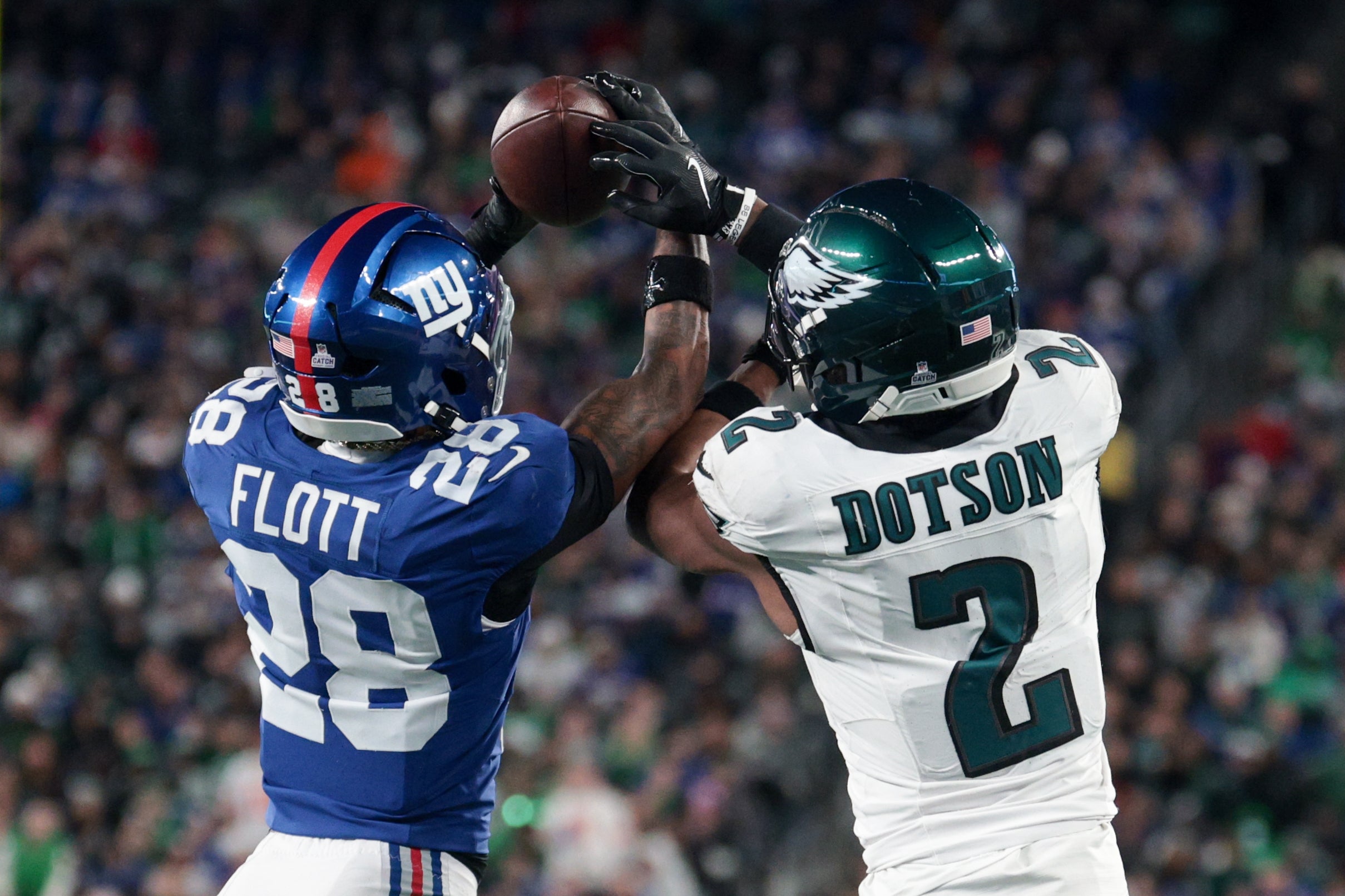 Oct 9, 2025; East Rutherford, New Jersey, USA; New York Giants cornerback Cor'Dale Flott (28) intercepts the pass intended for Philadelphia Eagles wide receiver Jahan Dotson (2) during the fourth quarter of the game at MetLife Stadium.