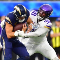 Oct 23, 2025; Inglewood, California, USA; Los Angeles Chargers quarterback Justin Herbert (10) ruses the ball against Minnesota Vikings linebacker Jonathan Greenard (58) during the first half at SoFi Stadium.