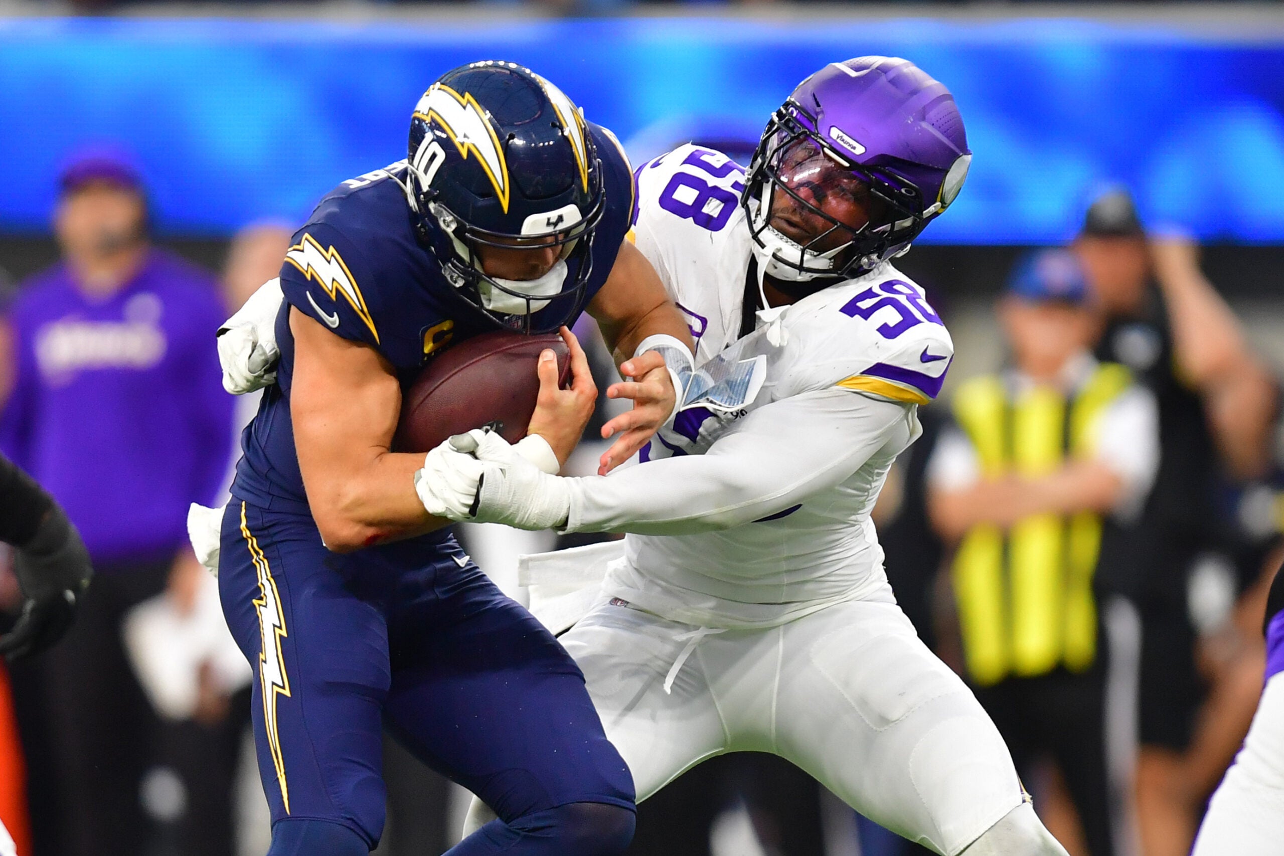 Oct 23, 2025; Inglewood, California, USA; Los Angeles Chargers quarterback Justin Herbert (10) ruses the ball against Minnesota Vikings linebacker Jonathan Greenard (58) during the first half at SoFi Stadium.