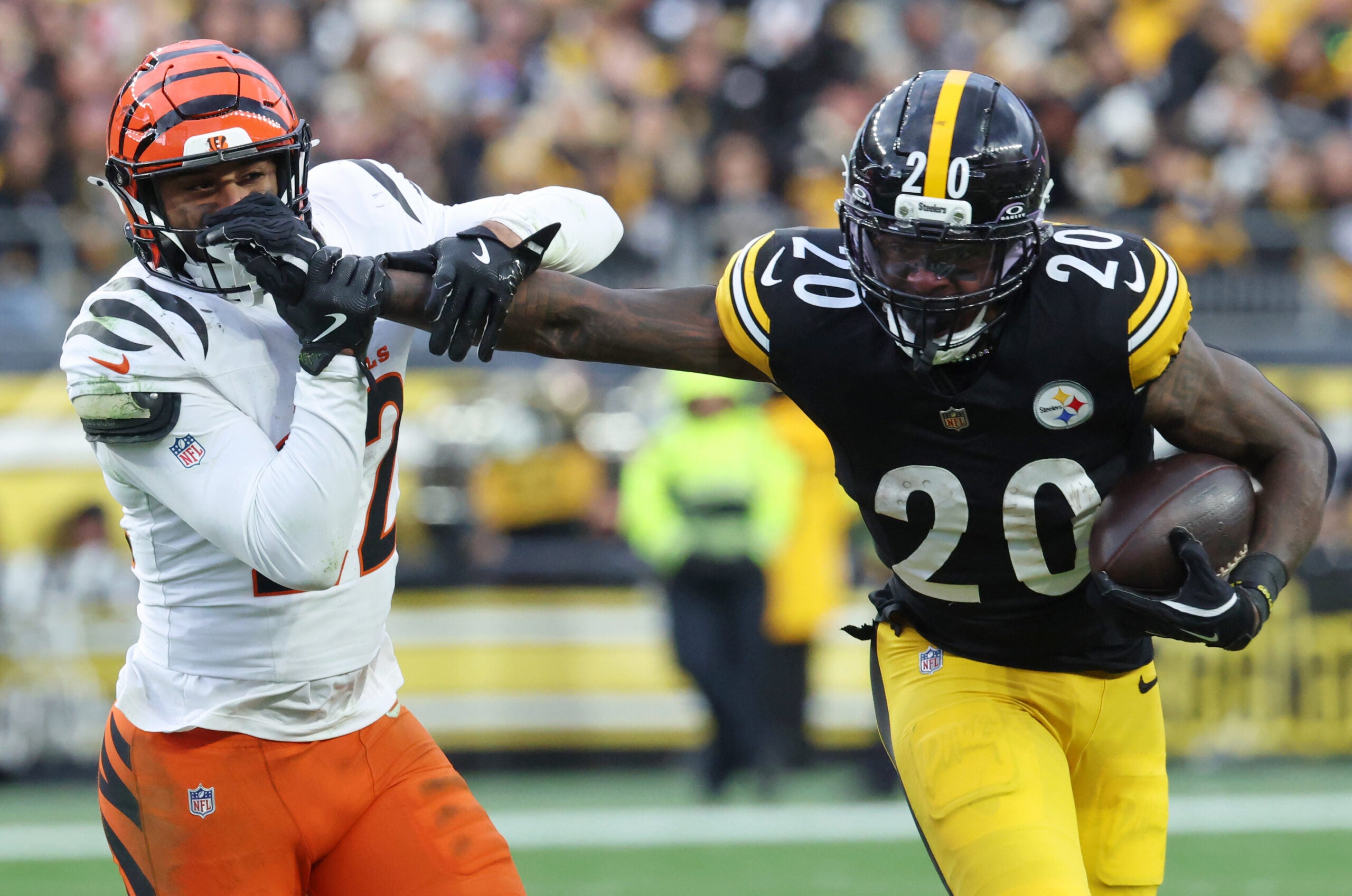 Nov 16, 2025; Pittsburgh, Pennsylvania, USA; Pittsburgh Steelers running back Kaleb Johnson (20) stiff arms Cincinnati Bengals safety Geno Stone (22) during the second half at Acrisure Stadium.